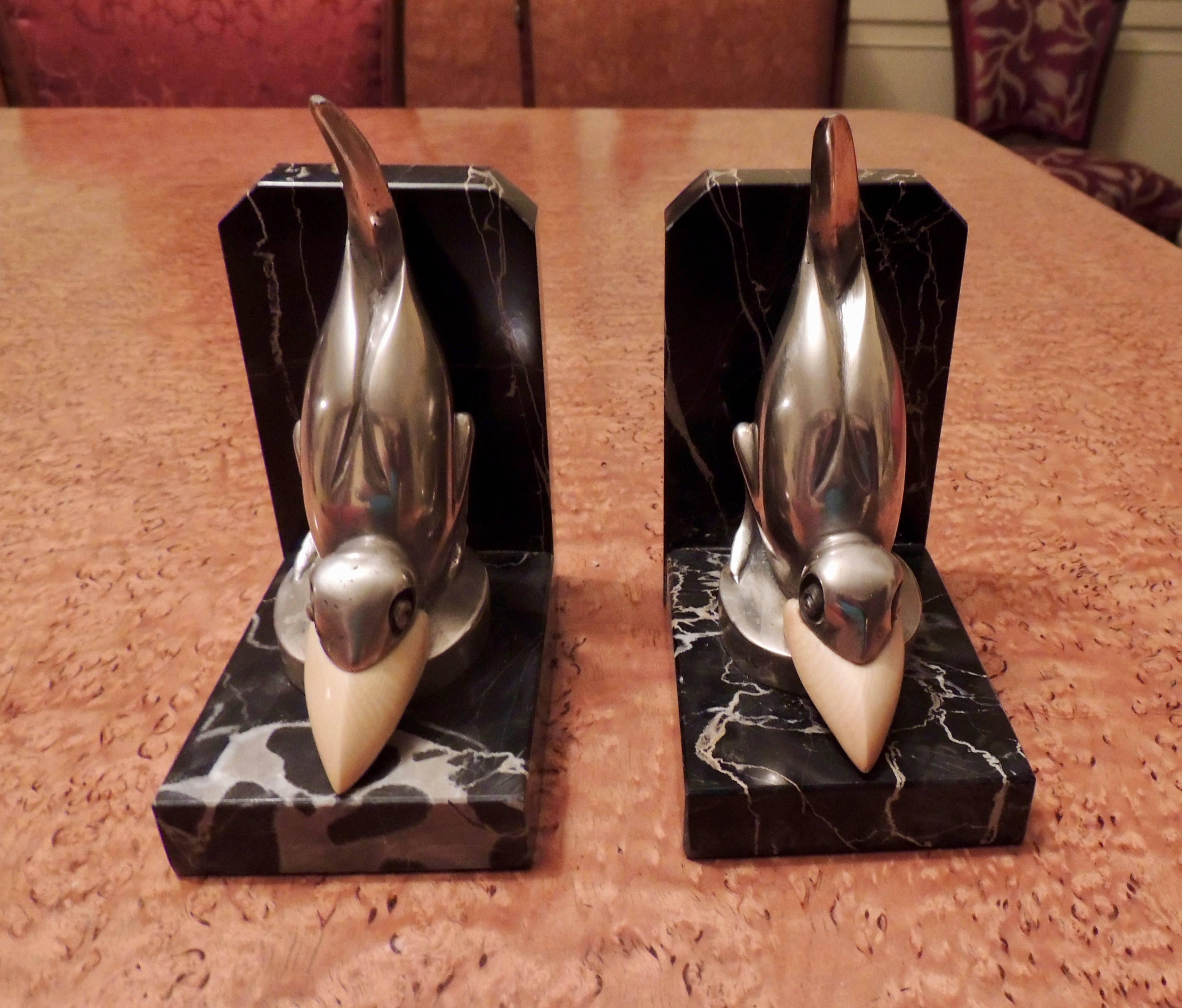 These Art Deco bookends by Marcel Bouraine are playful pieces made of silvered bronze and mounted on Portoro marble. They are signed in the circular base M.Bouraine. This figure was also produced as a fancy automobile “mascot”, to be affixed to the