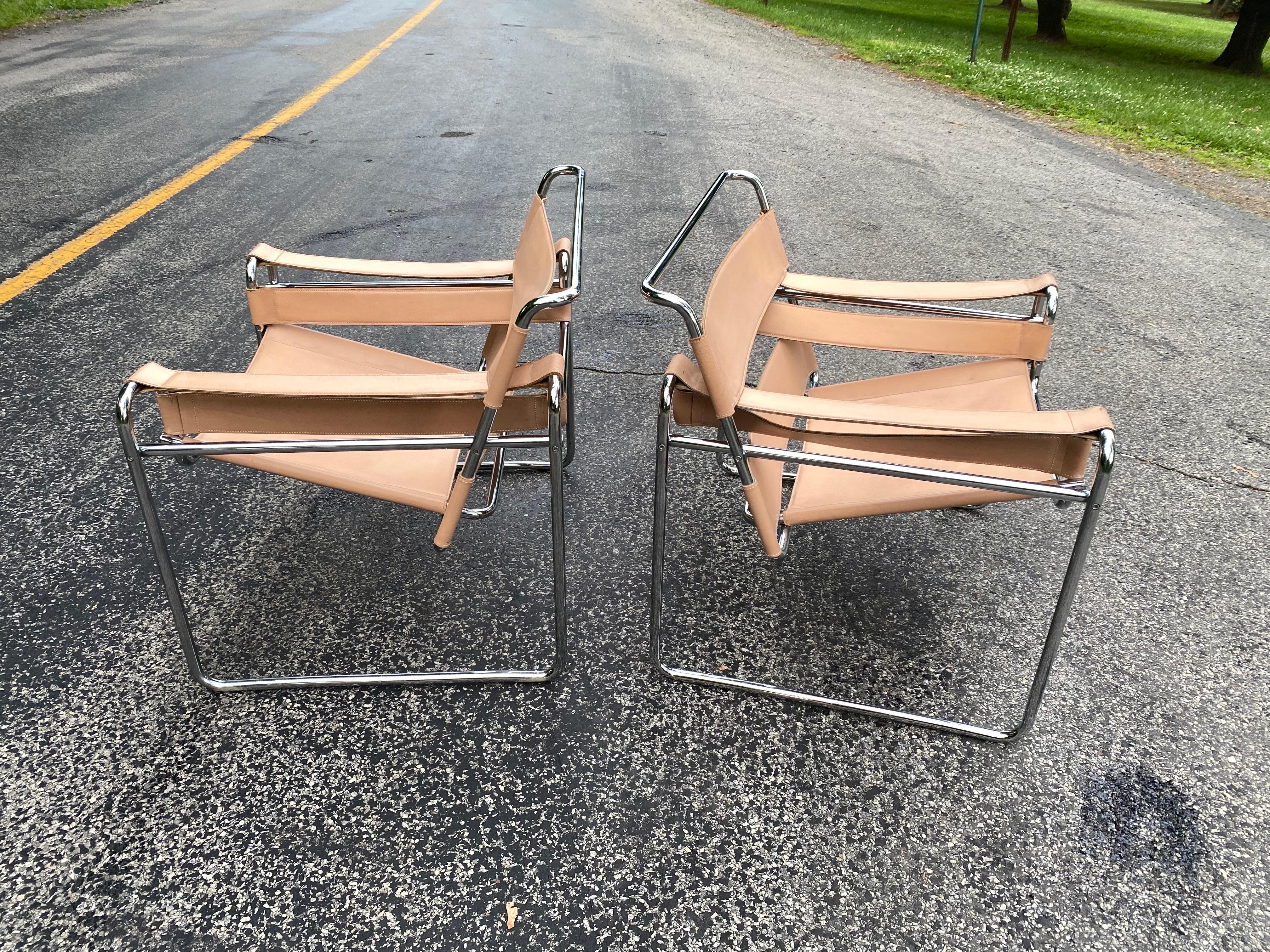 Pair of Marcel Breuer Wassily chairs in a creamy colored leather. Leather shows a nice amount of Patina, as seen in photos. Chrome is very clean! Leather shows wear at armrest areas but all still solid with no missing or loose stitching to leather.