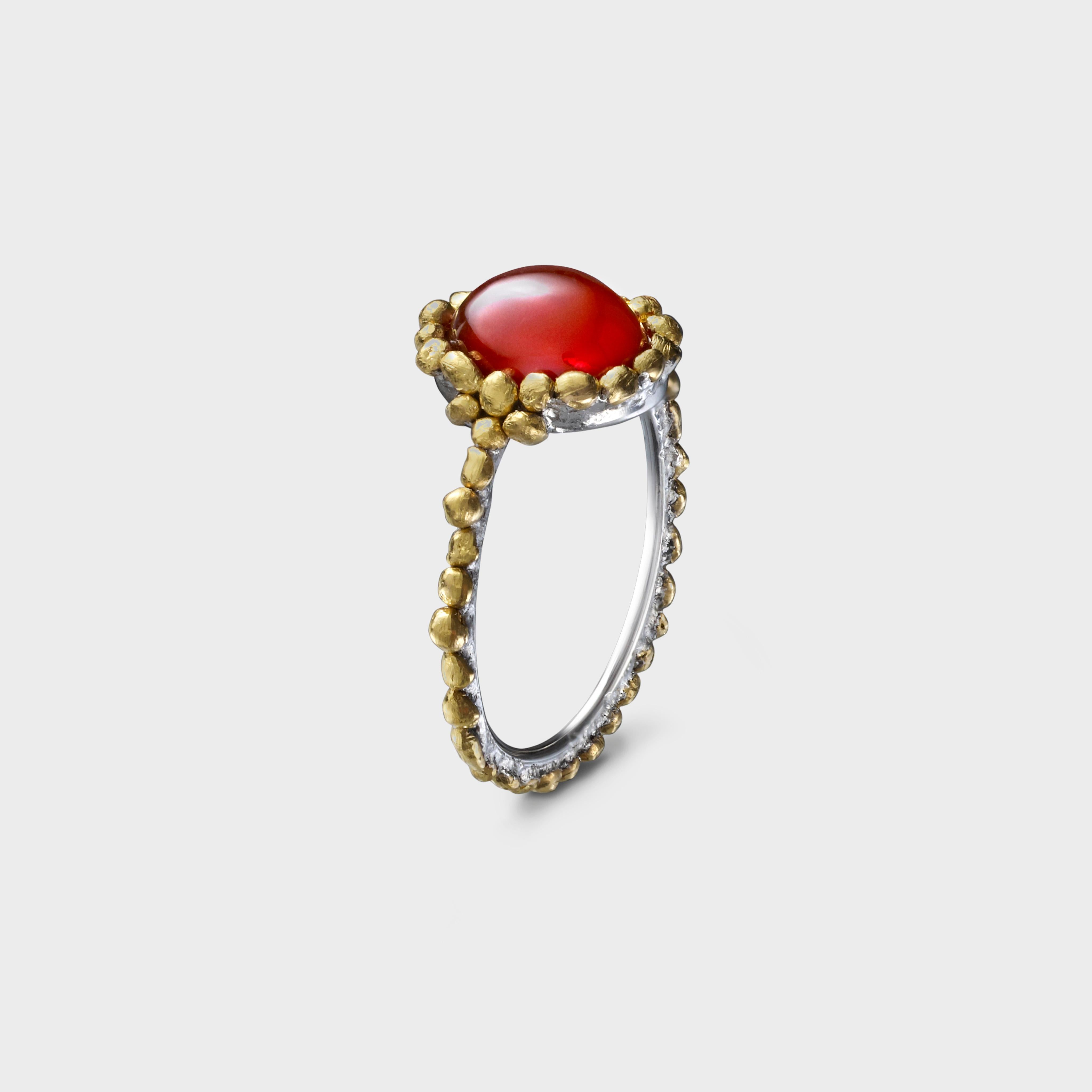 A beautiful reddish fire opal that perfectly compliments the sun rays of the 24 karat gold pebbles on the halo around it; bold and fun.  The pure gold pebbles are nestled securely into a platinum platform.   Part of a playful collection inspired by