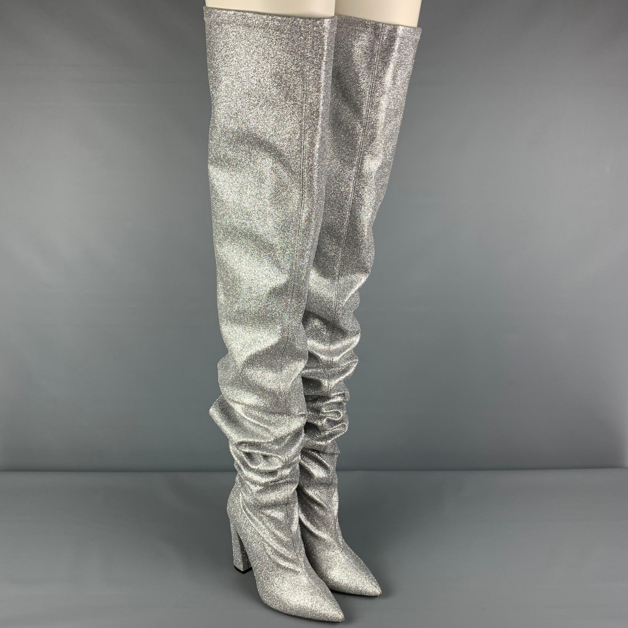 MARCELL VON BERLIN boots comes in a silver metallic glitter leather featuring a thigh high length, pointed toe, slip on, and a chunky heel. Includes box. Made in Spain.

Very Good Pre-Owned Condition.
Marked: 40
Original Retail Price: