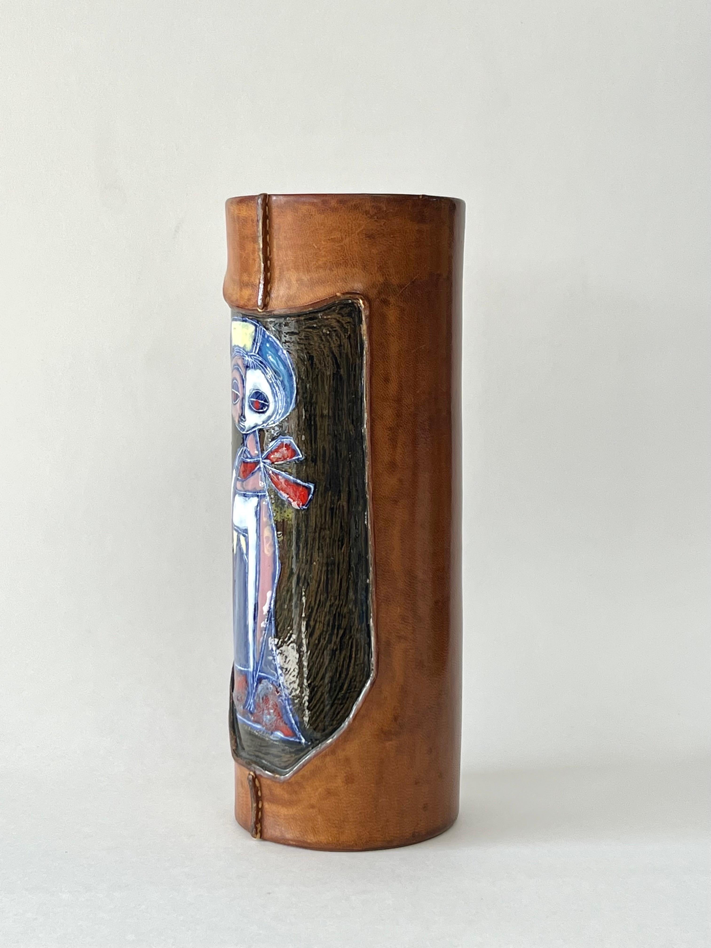 A cylindrical vase by Marcello Fantoni. 
It is ceramic partially enveloped in leather. The leather creates a reveal for a stylish woman to appear looking out directly at the viewer. Signed on bottom.