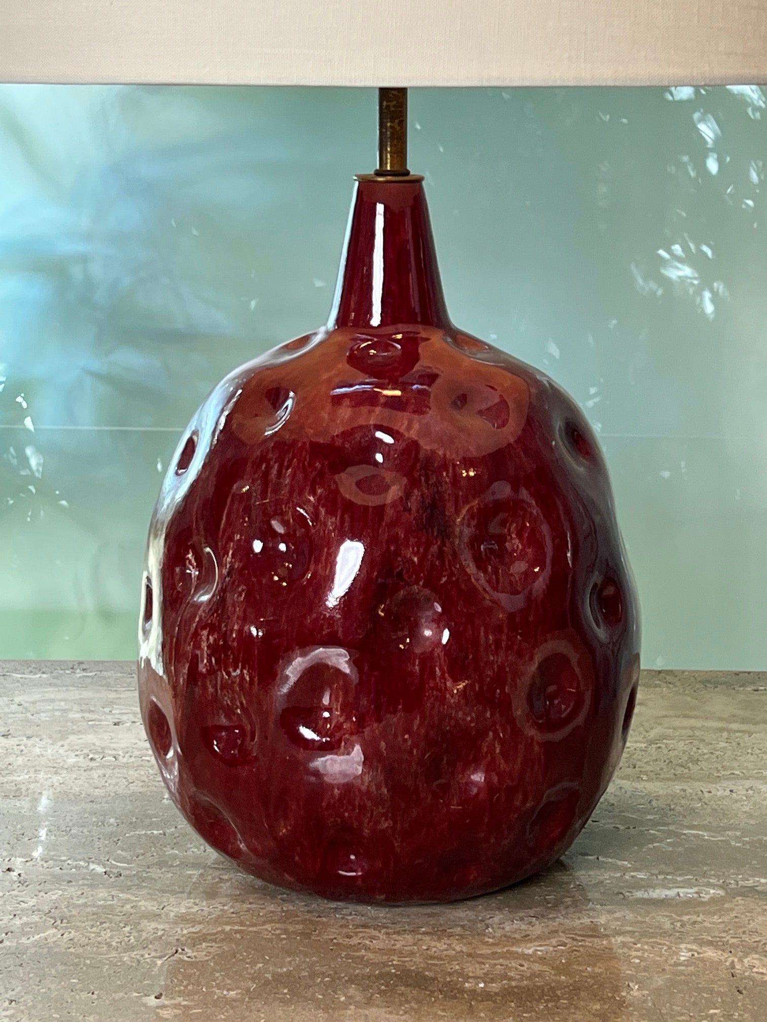 A beautifully glazed cranberry colored dimpled ceramic lamp by Marcello Fantoni. Signature to bottom. 
Ceramic measures 12