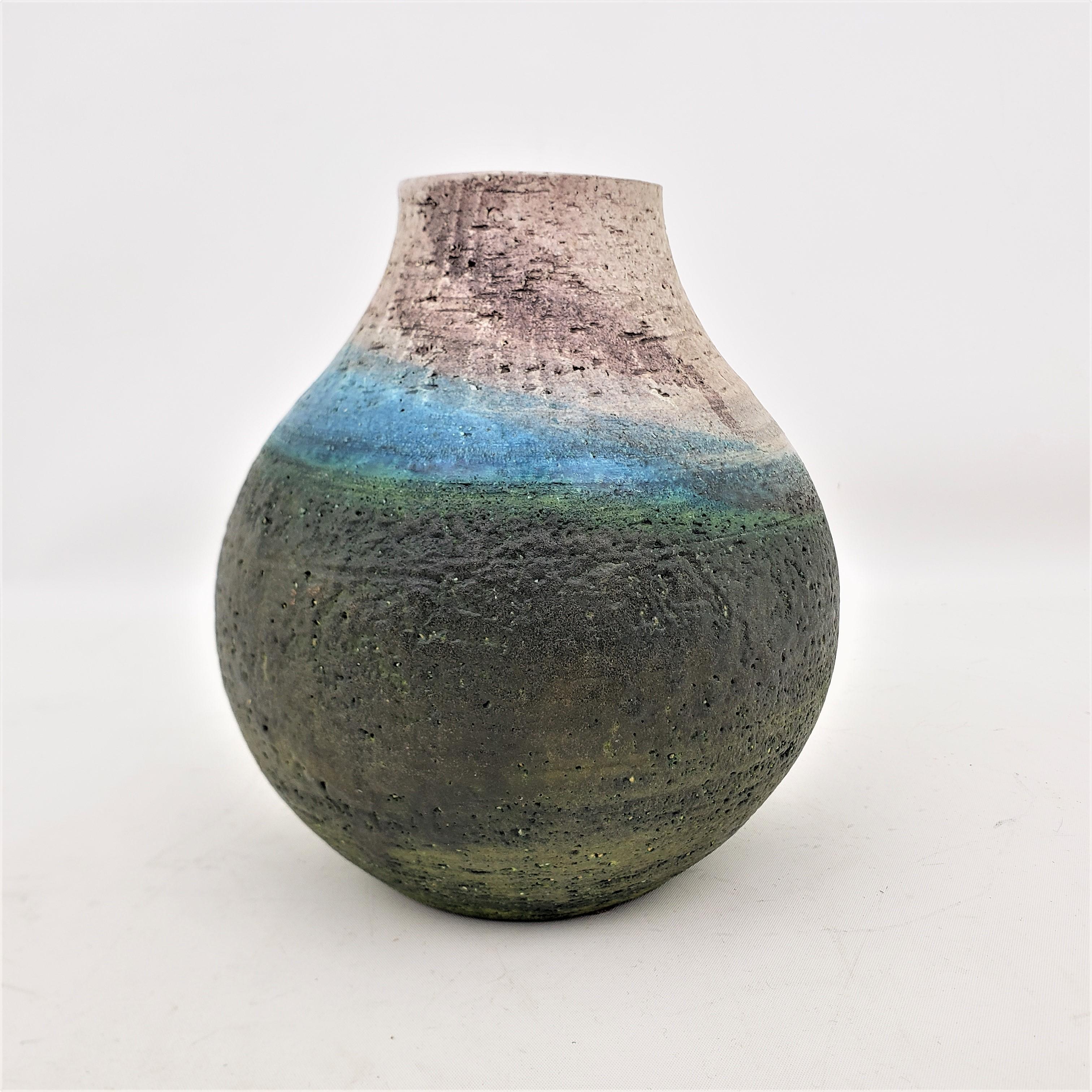 This art pottery vase was done by the renowned Marcello Fantoni of Italy in approximately 1960 in the period Mid-Century Modern style. The vase is done with a thick dark brown clay with a bulbous form and is decorated with swirled bands of blue and