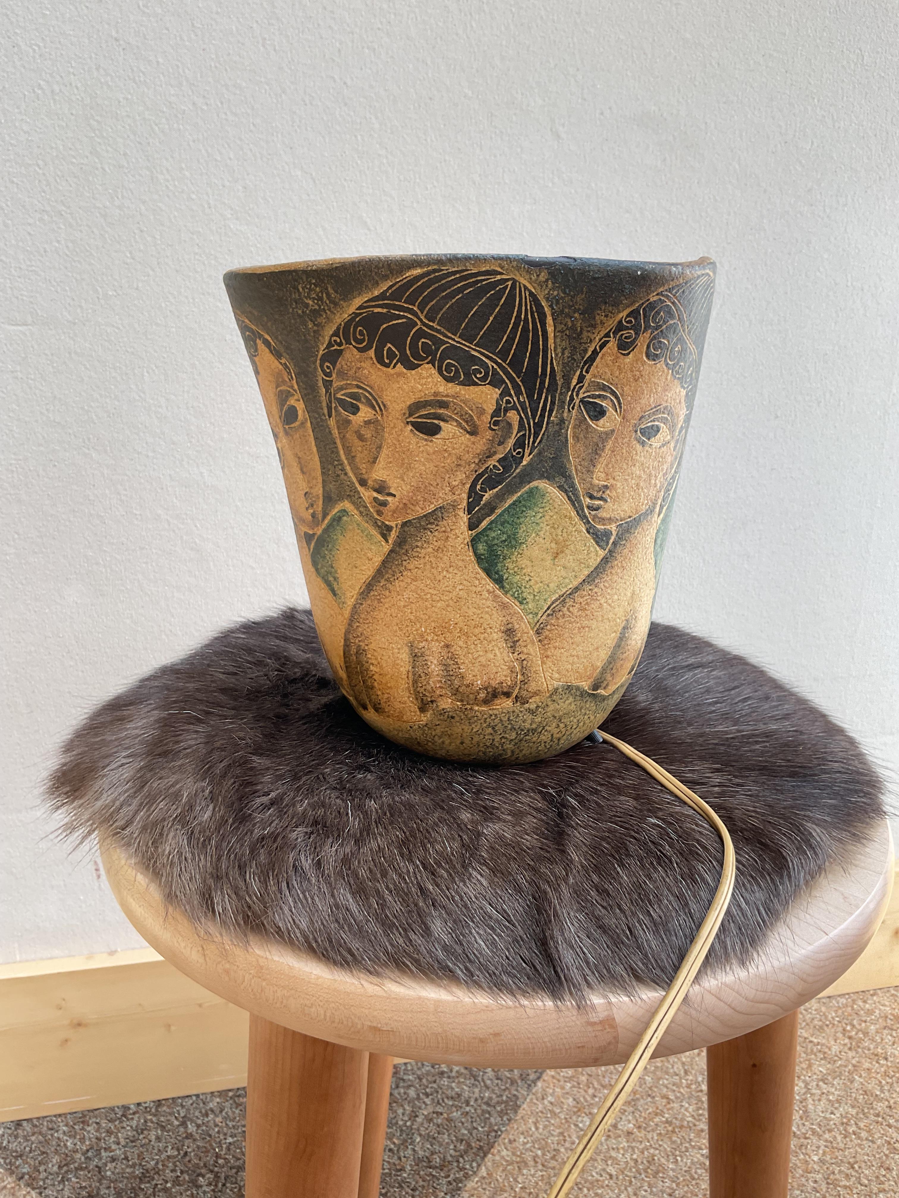 Lámpara de Studio Pottery firmada por el emblemático ceramista italiano Marcello Fantoni, realizada en la década de 1950. Esta llamativa pieza de mediados de siglo presenta una forma acampanada y ahusada con figuras estilizadas pintadas a mano en