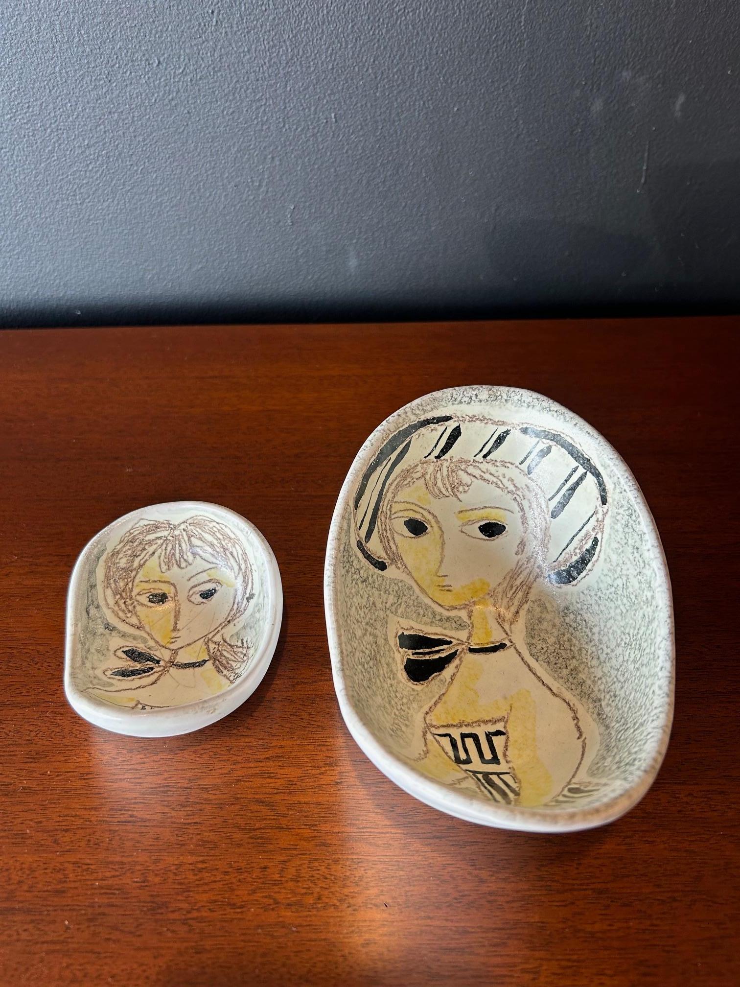 Pair of Italian curvy small ceramic dishes featuring stylized women's portraits by Marcello Fantoni for Raymor. Dimensions for the larger dish: 3.25 H x 6.5 W x 4.5 D inches, and the smaller dish: 2 H x 3.5 W x 3 D inches. Price listed is for both