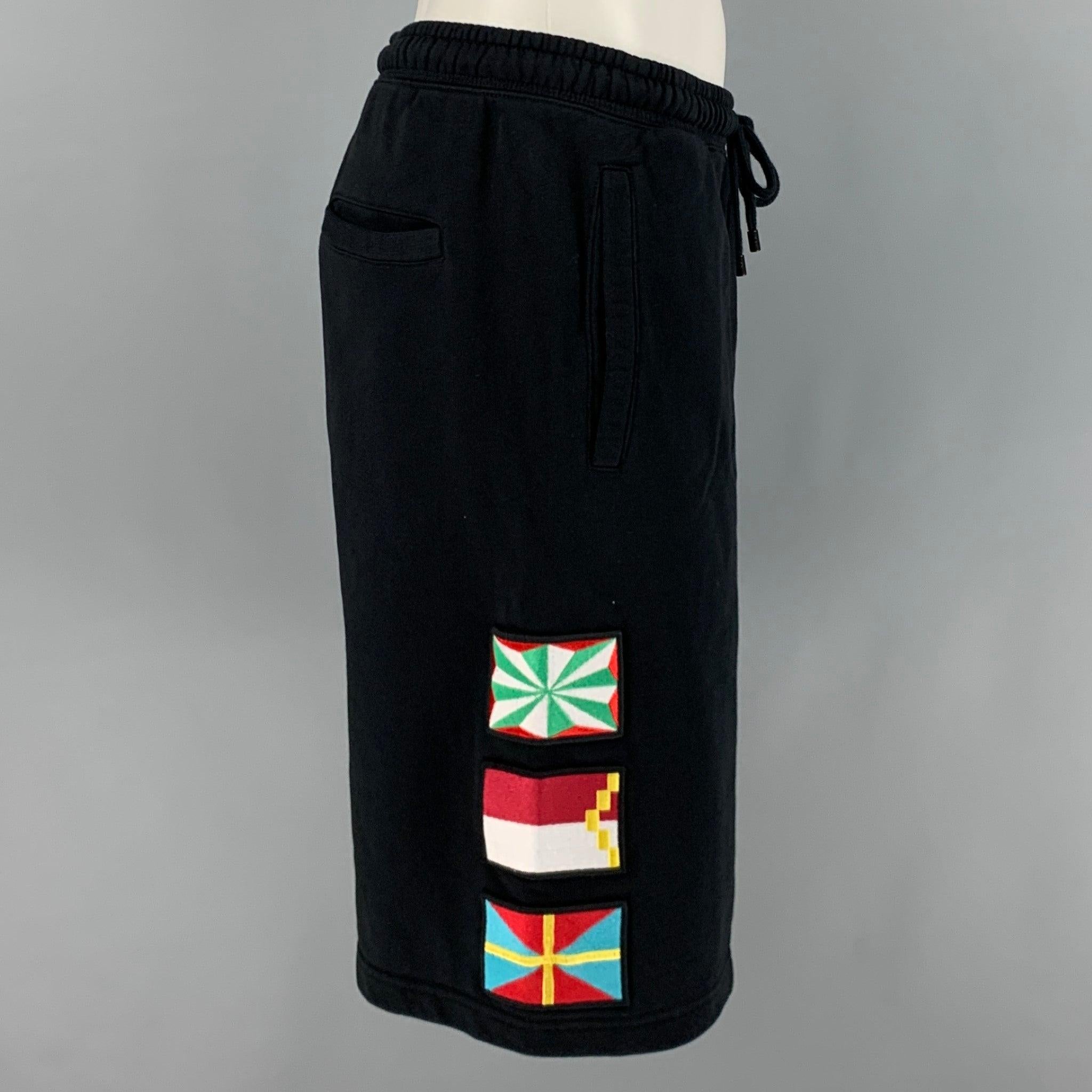 MARCELO BURLON shorts
in a
black cotton fabric featuring multi-color flag appliques, relaxed fit, and drawstring waist. This item has been altered. Made in Portugal.Very Good Pre-Owned Condition. Minor marks. 

Marked:   S 

Measurements: 
  Waist: