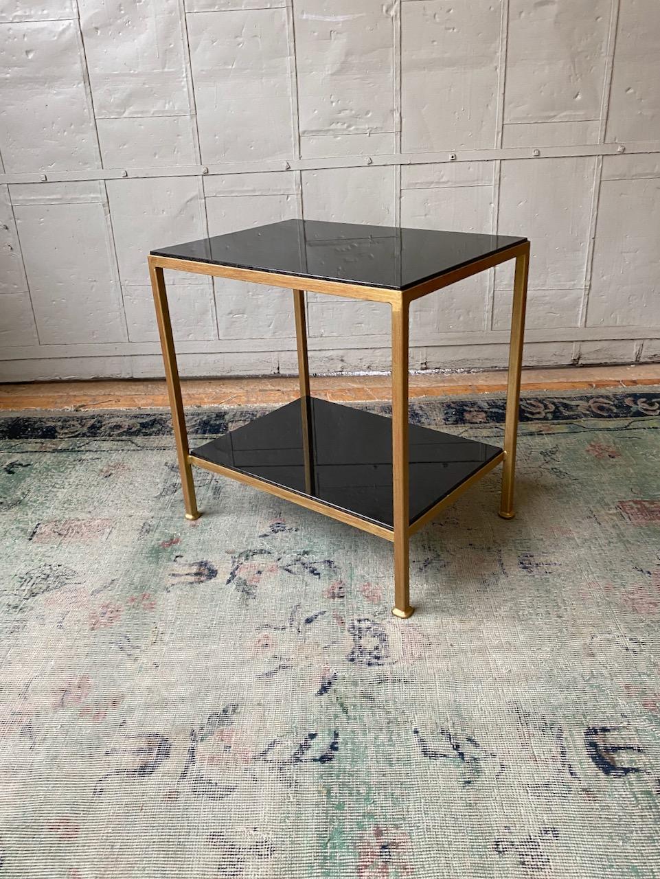This well proportioned side table features an iron frame in a hand distressed gold finish with an undercoat of Venetian red. The shelves are polished absolute granite. This is a floor sample from our discontinued Reeditions line. The sample is in