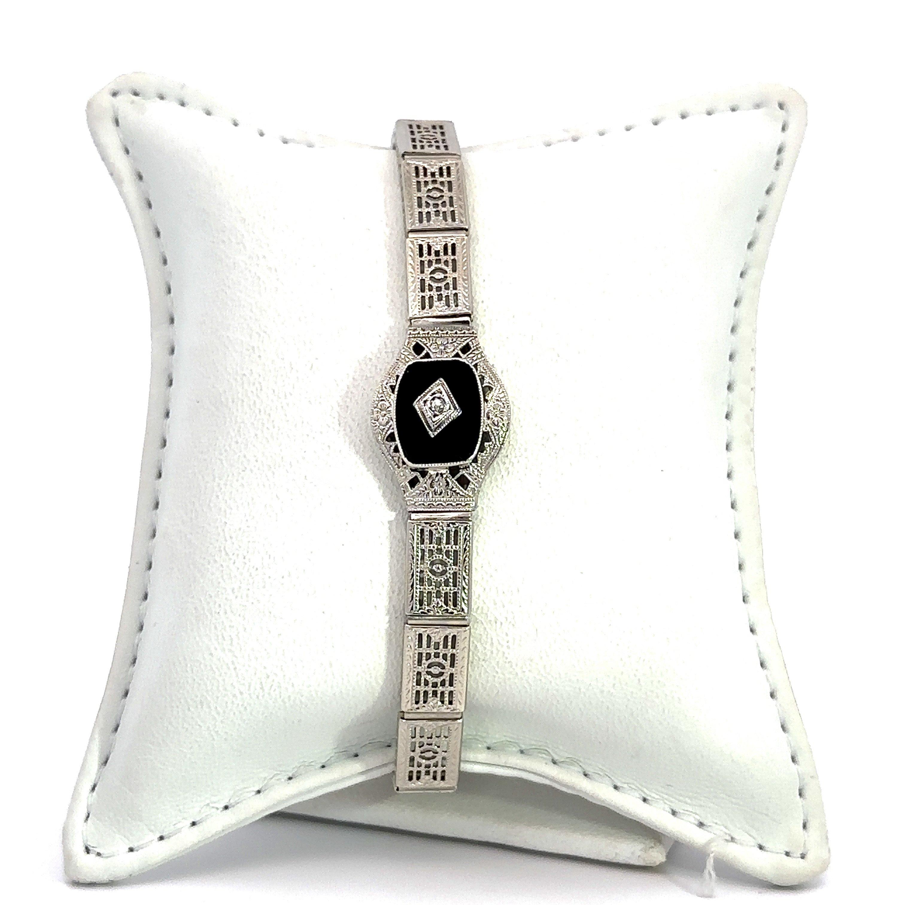 Questo bracciale antico Art Deco è stato creato da Ostby & Barton e risale agli anni Venti.
È realizzato in oro bianco 14KT in stile filigrana.
Presenta una pietra centrale in onice naturale con un diamante rotondo naturale a taglio antico