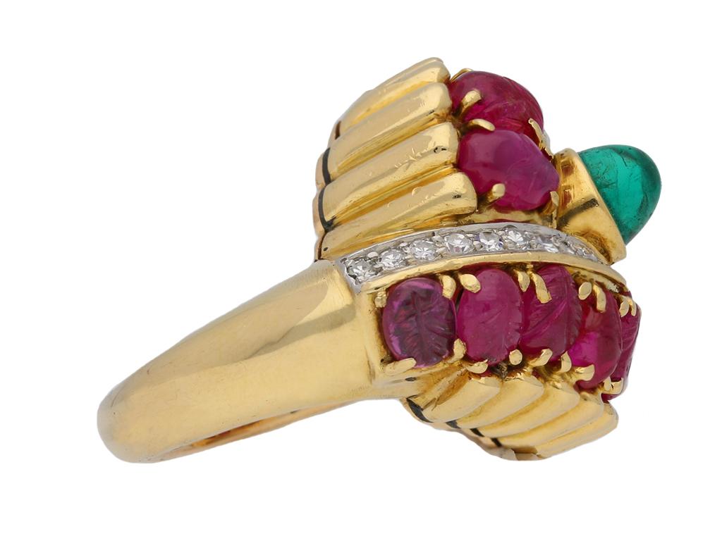 Marchak cabochon emerald, carved ruby and diamond ring. Set centrally with a round cabochon natural emerald with no colour enhancement in an open back rubover setting with an approximate weight of 1.00 carats, bordered by two rows of fourteen oval