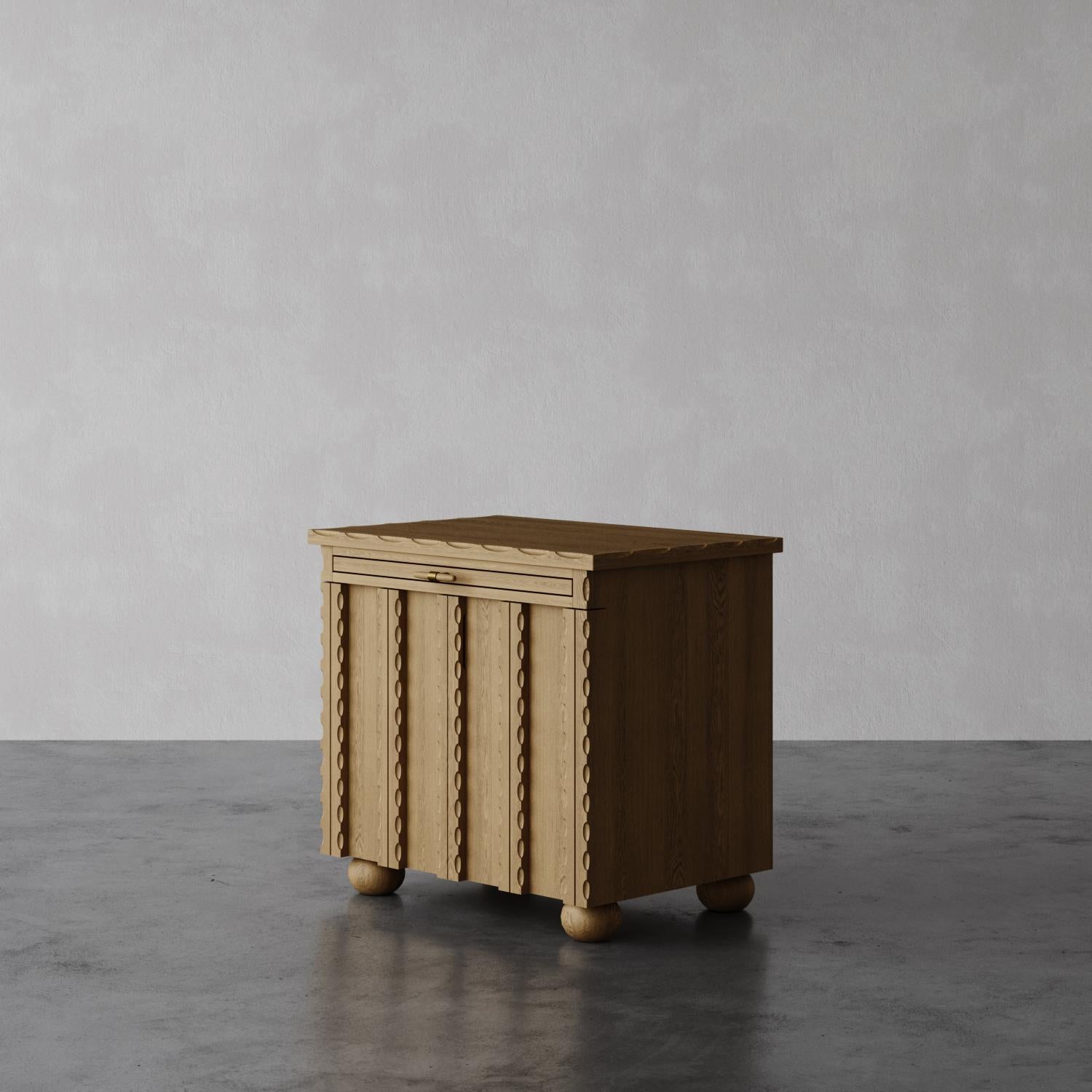The Marchand nightstand features elegantly scalloped edge detailing and textural door fronts, creating a standout design for any bedroom. Designed for convenience, it includes a pull-out shelf for extra bedside storage and boasts unique custom