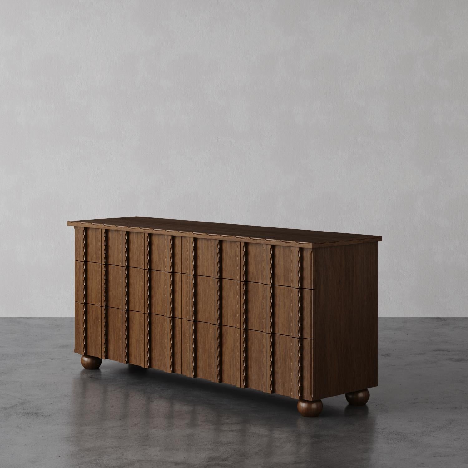 The Marchand 6-drawer dresser showcases elegantly scalloped edge detailing and textural drawer fronts, making it a distinctive piece in any bedroom. It sits on minimal turned legs, blending classic charm with a modern design. The detailed carved