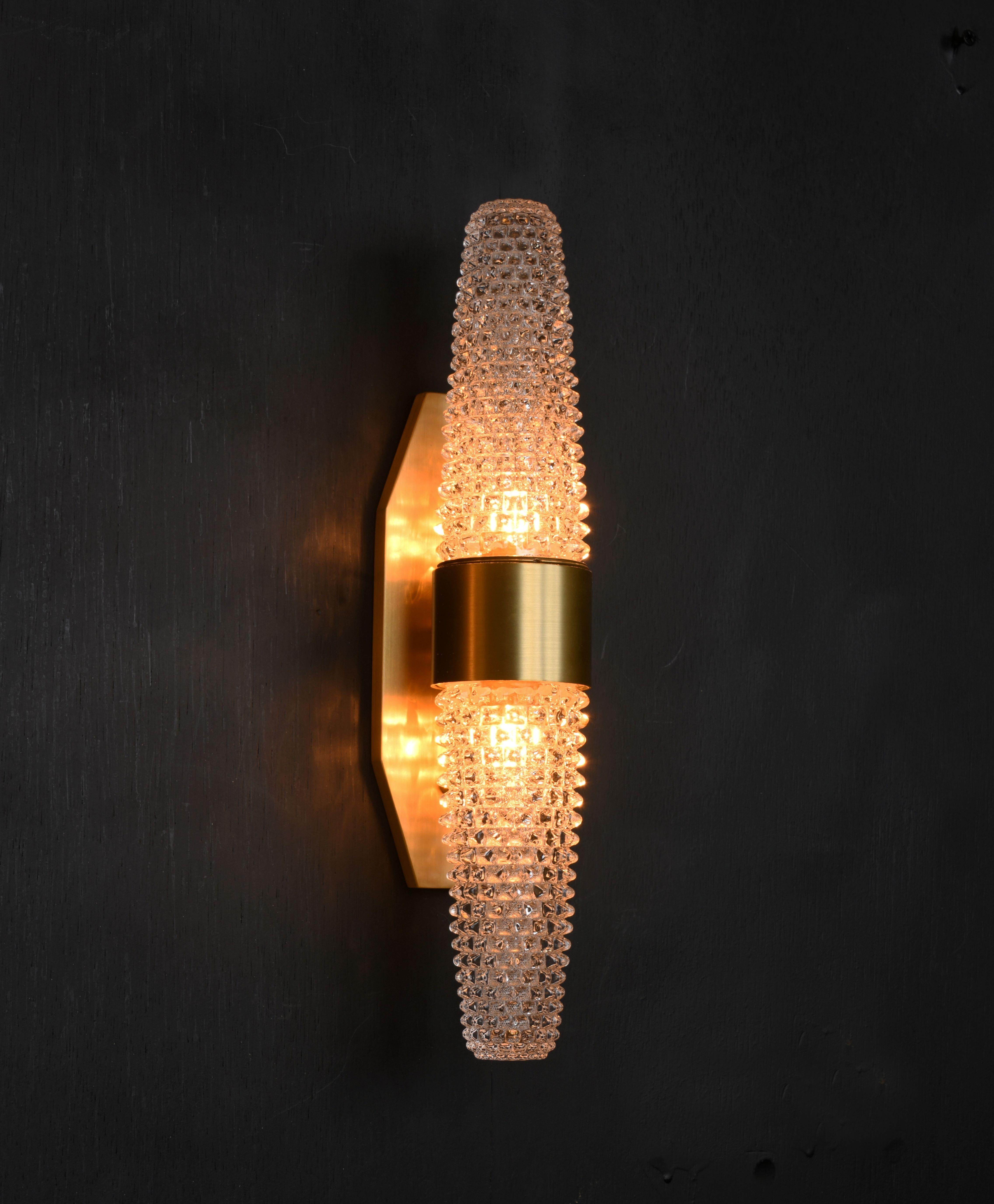 Spiked double glass cones in the ancient Rostrato style sparkle on the modern arms of bold brushed brass with machined details.

Models in the collection are individually hand-crafted by the skilled artisans in our studio. Custom versions tailored