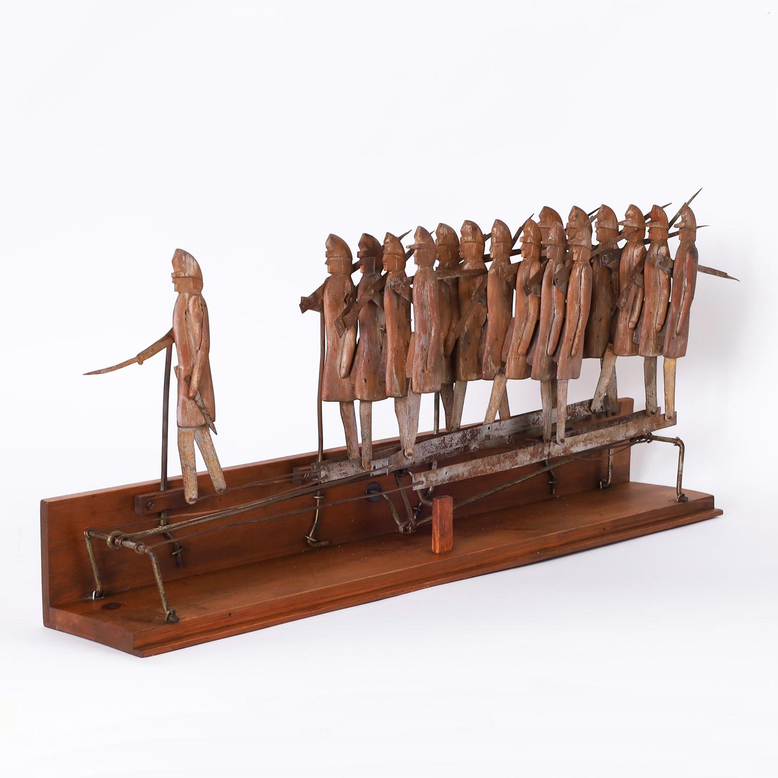 Antique mechanical toy ambitiously crafted with a metal mechanism moved by a crank in the back, sending civil war union soldiers, carved in pine with their distinctive caps, marching to battle.