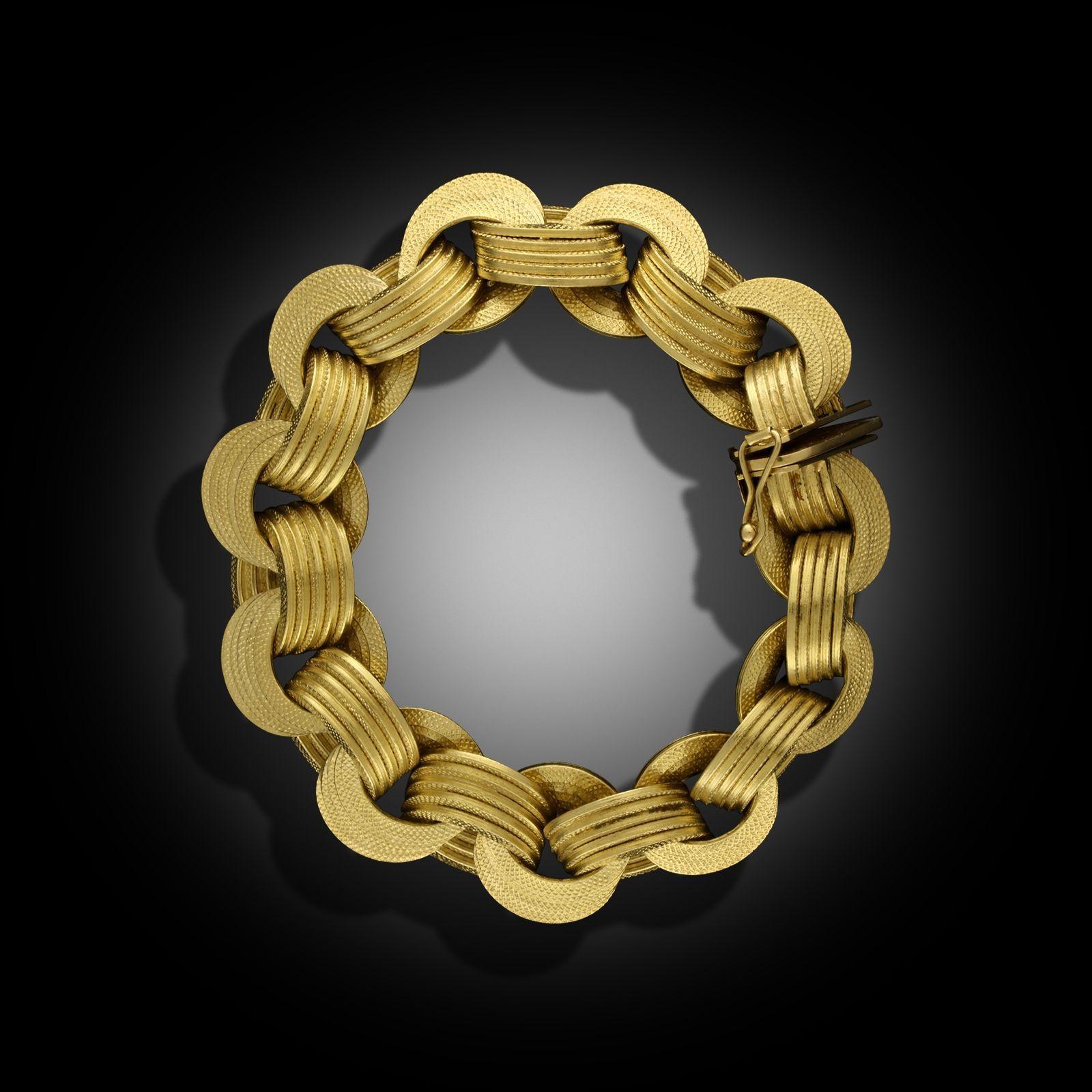 A vintage yellow gold bracelet by Marchisio, circa 1970. The bracelet is designed as flexible interlocking 18ct yellow gold circular links, each textured with an engine turned pattern and terminates with a concealed tongue and box
