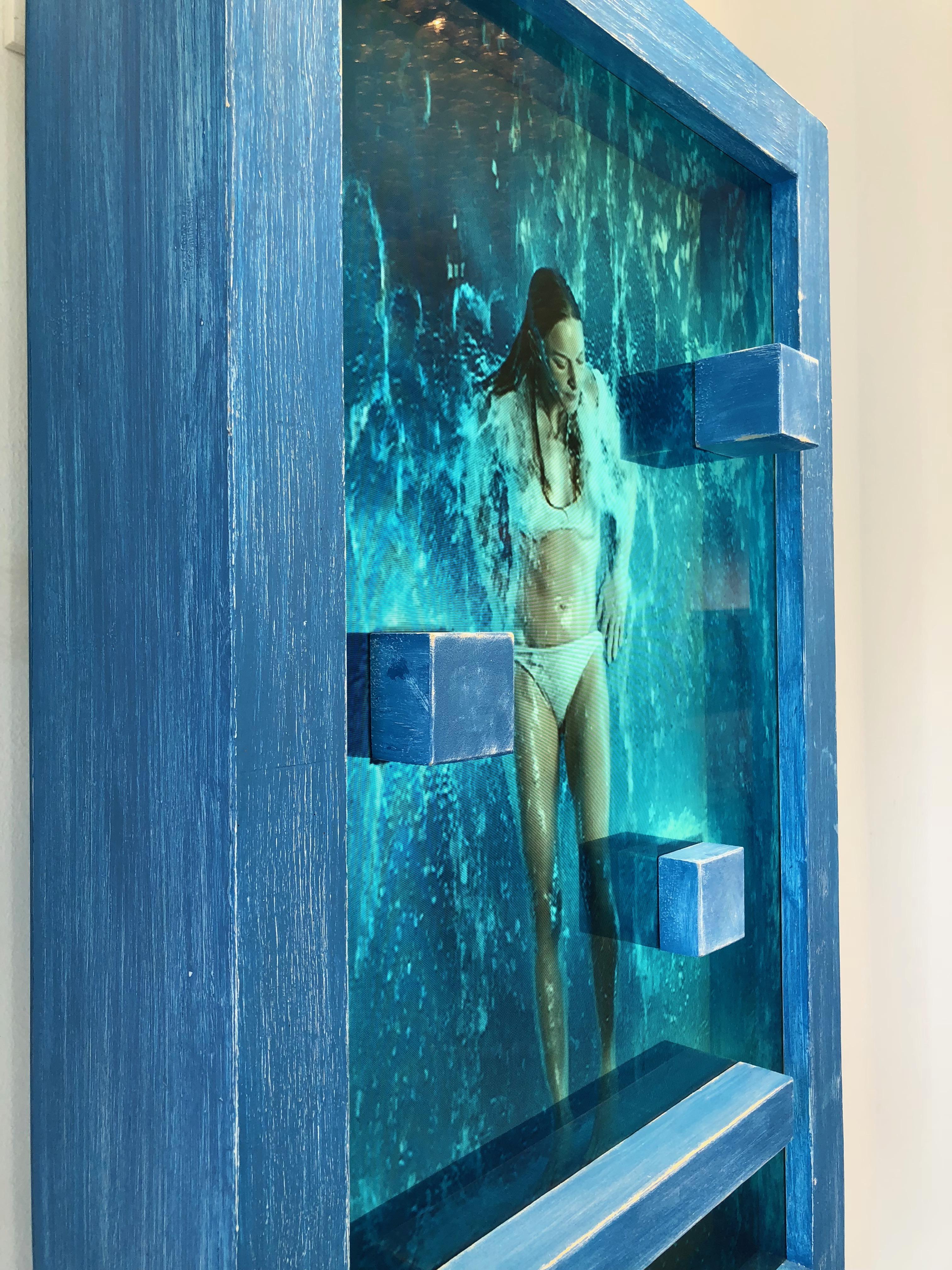 MARCK
 
'Waterfall' features 3 - 20 minute loops each of a different woman (changed by a button at base of the frame) under a continuous waterfall, interacting with blocks and a platform that exist both in the video and on the exterior of the