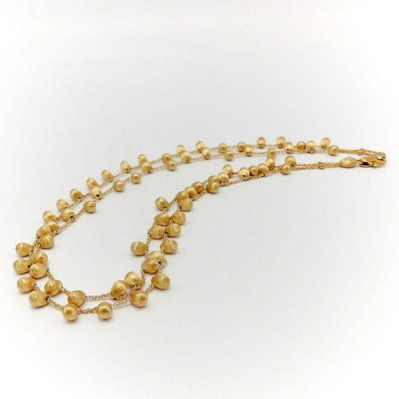 This is a stunning Marco Bicego “Acapulco” necklace in 18K gold. It is designed as a double strand with cable chains suspending textured gold beads. Every piece of Marco Bicego’s jewelry is handmade. The hand engraving that is present on the beads