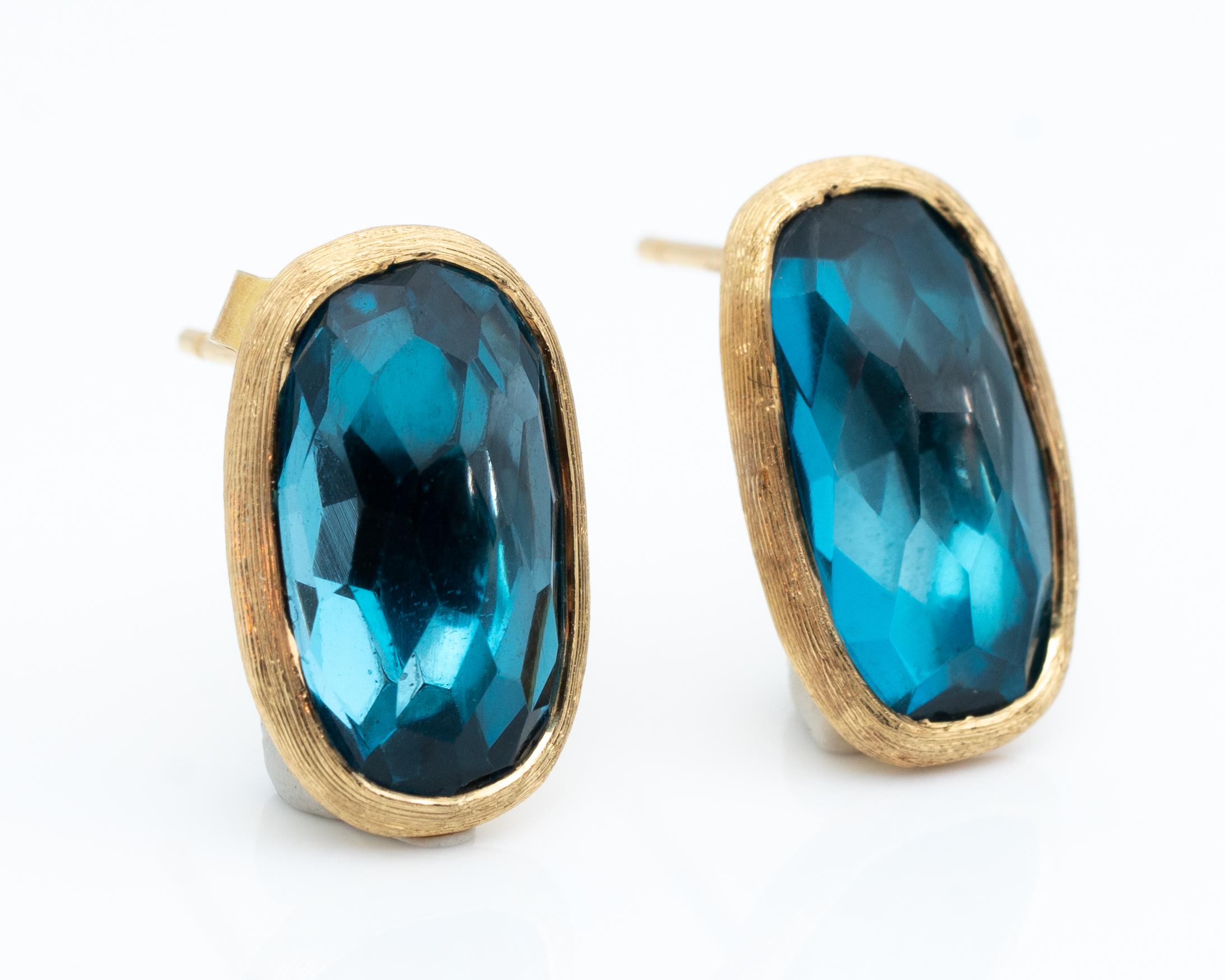 Feature:
Blue Topaz with visible facets, elongated oval shape 
Circa 1990s, Made in Italy
Push Back Earrings
Iconic Designer Marco Bicego

Item Details:
Metal Type: 18 Karat Yellow Gold
Weight: 4.13 grams 
Measures: 15 millimeter x 10 millimeter 

