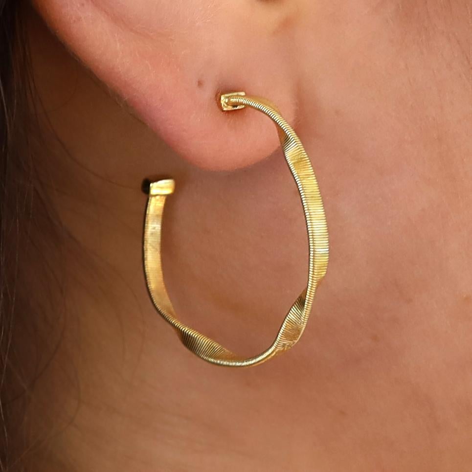 Aggiungi questi classici orecchini a cerchio in oro giallo 18 carati di Marco Bicego degli anni '90 alla tua collezione e goditi il lusso di tutti i giorni. Il design modernista è caratterizzato da una forma unica e sinuosa e da un motivo lineare e