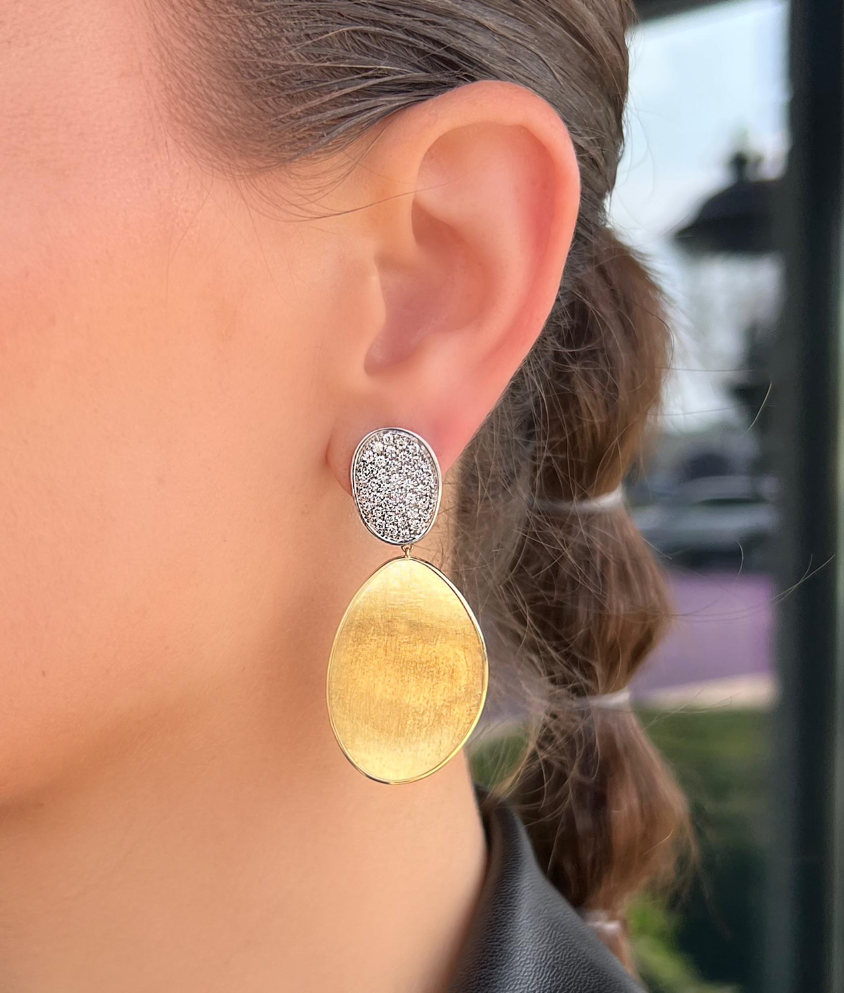 These lovely 18K Yellow Gold and Diamond drop earrings are the perfect addition to any collection. They are instantly recognizable as Marco Bicego and are excellent for a night out. The earrings feature 2 smaller diamond pave disks perched on top of