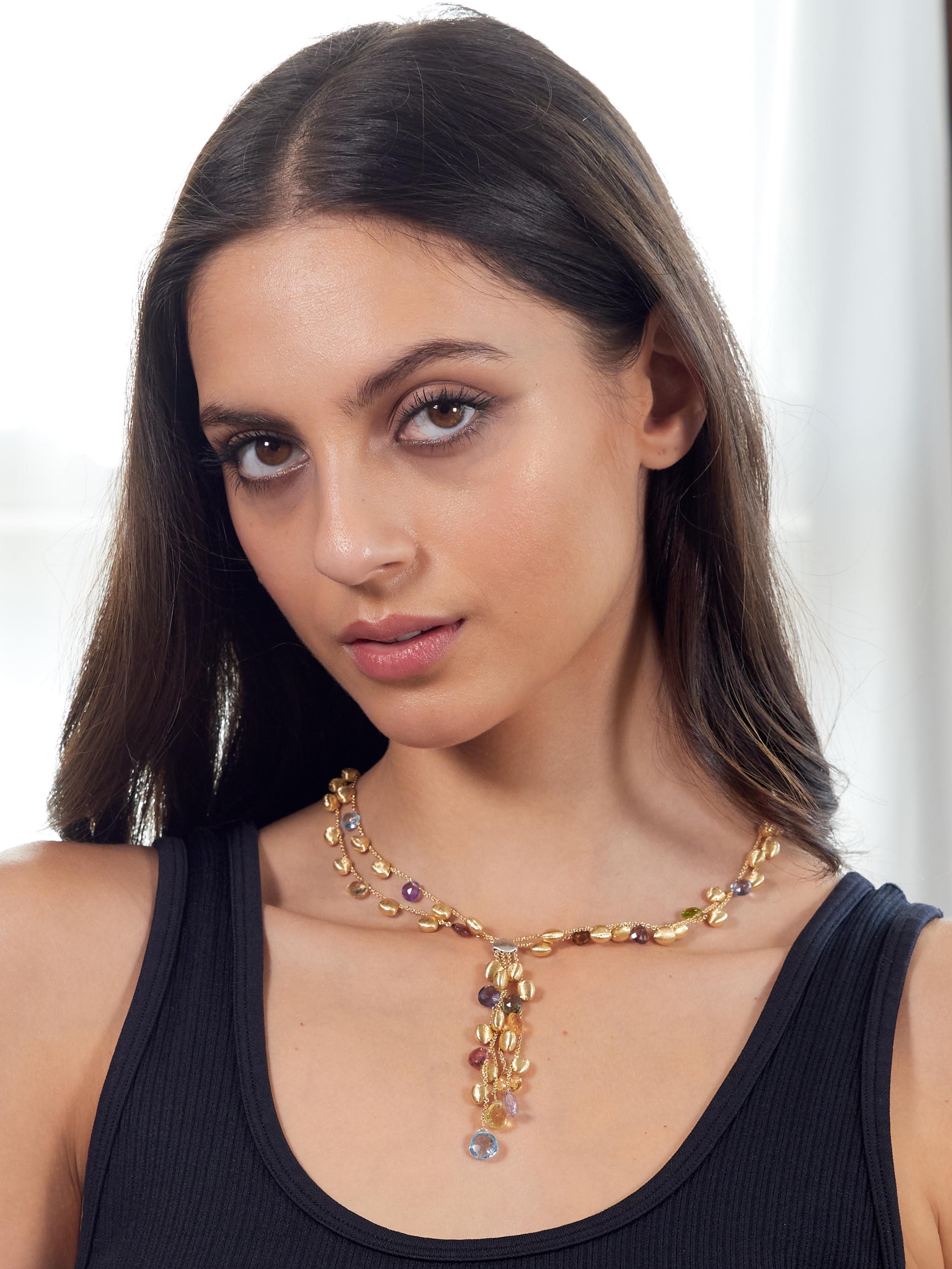 Designed as lariat style necklace of four cable chain strands suspending fringe with blue topaz drops
Cable chain strands are beaded throughout with brushed gold and multi-gem beads
Gemstones are pink tourmaline, green tourmaline, blue topaz,