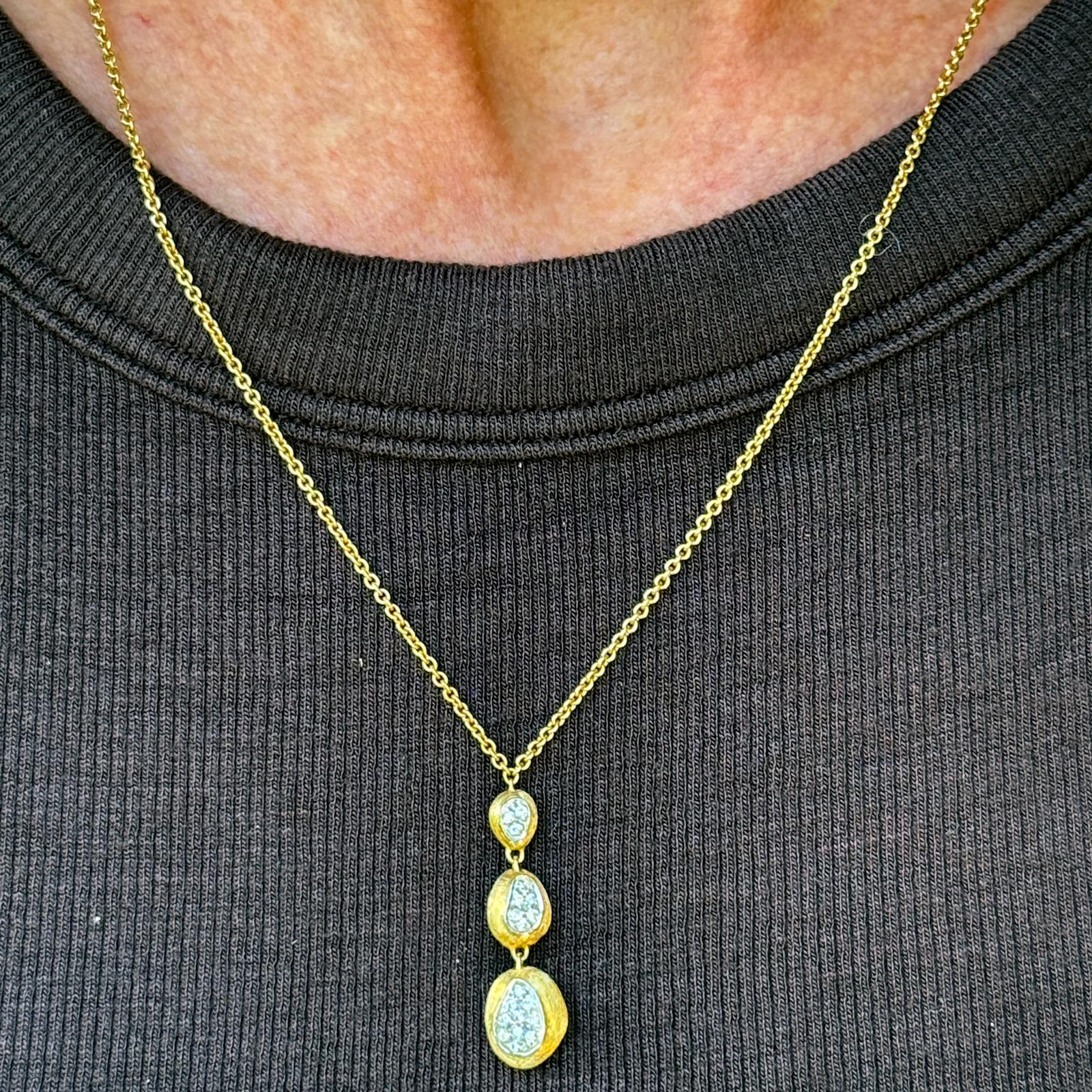 From Marco Bicego’s iconic Siviglia collection, this elegant 18K yellow gold necklace features a trio of softly hand-engraved oval drops, creating a refined, organic texture characteristic of the designer’s signature style. Accented with 19 round