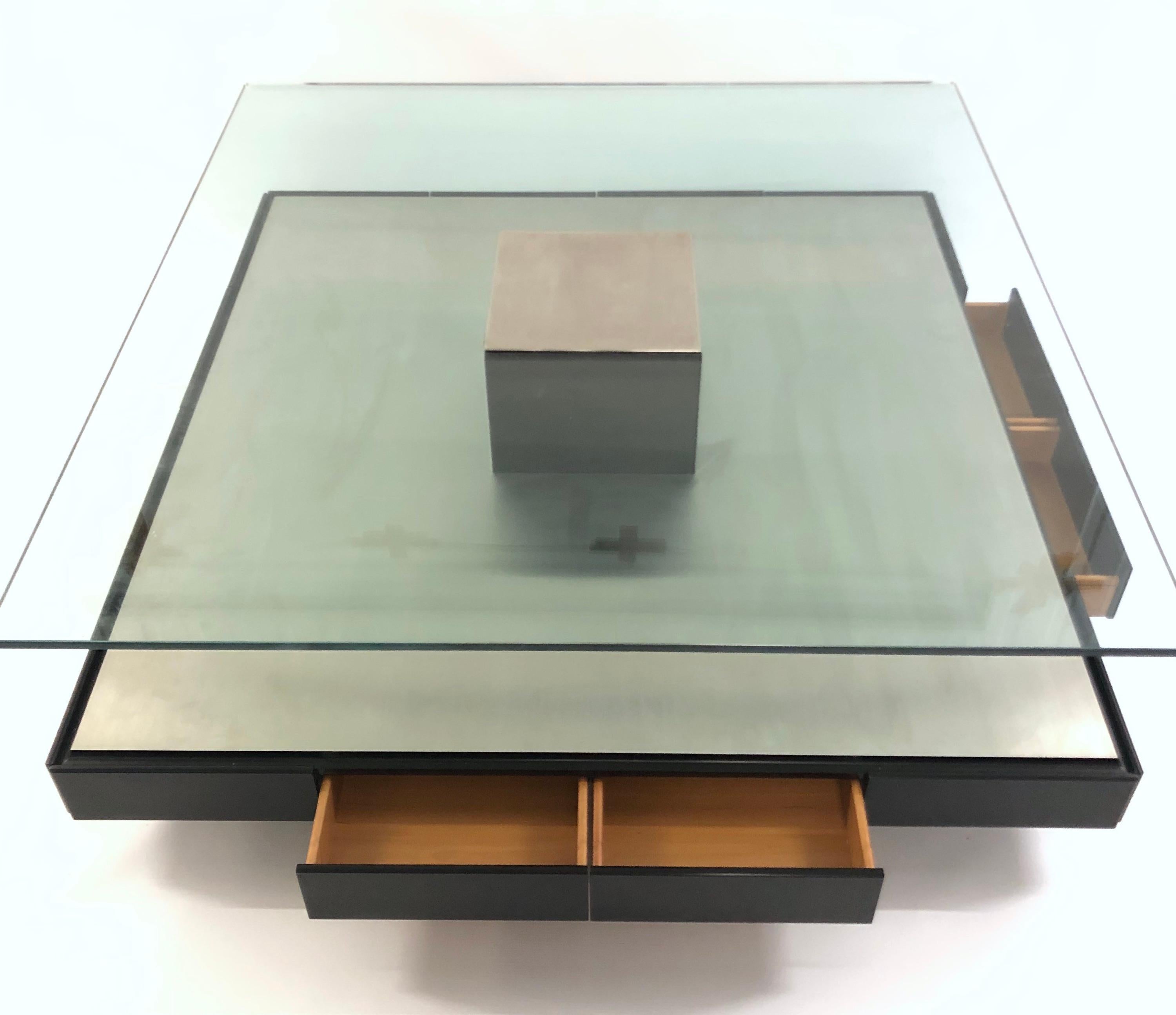 Designed in 1971 for Italian manufacturer Tecno by Marco Fantoni.
Consisting of brushed steel base with glass top.
Eight drawers located around the black lacquered plinth base. 
Central black lacquered block supporting the glass top. 
Central