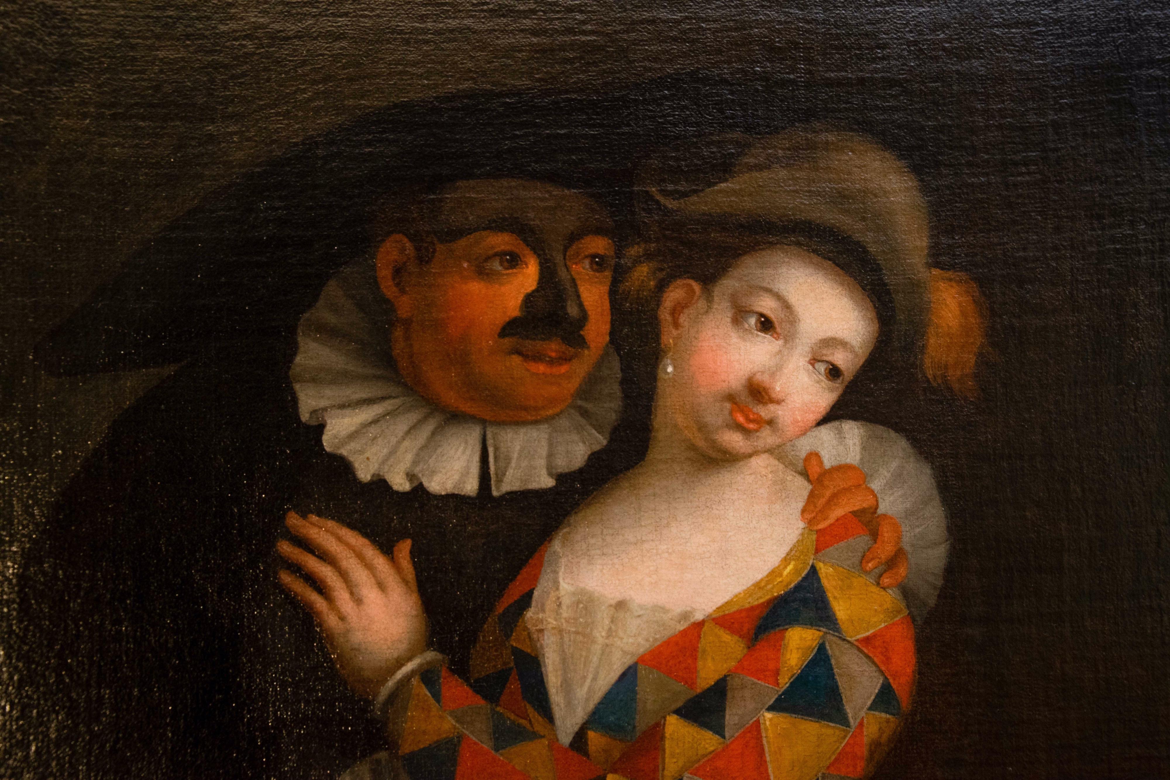 The painting depicts a gallant carnival scene.
A woman dressed as a harlequin with the classic multicolored triangle dress is being embraced by a man dressed as Balanzone with his typical black dress and the mask hiding his face.
The two are