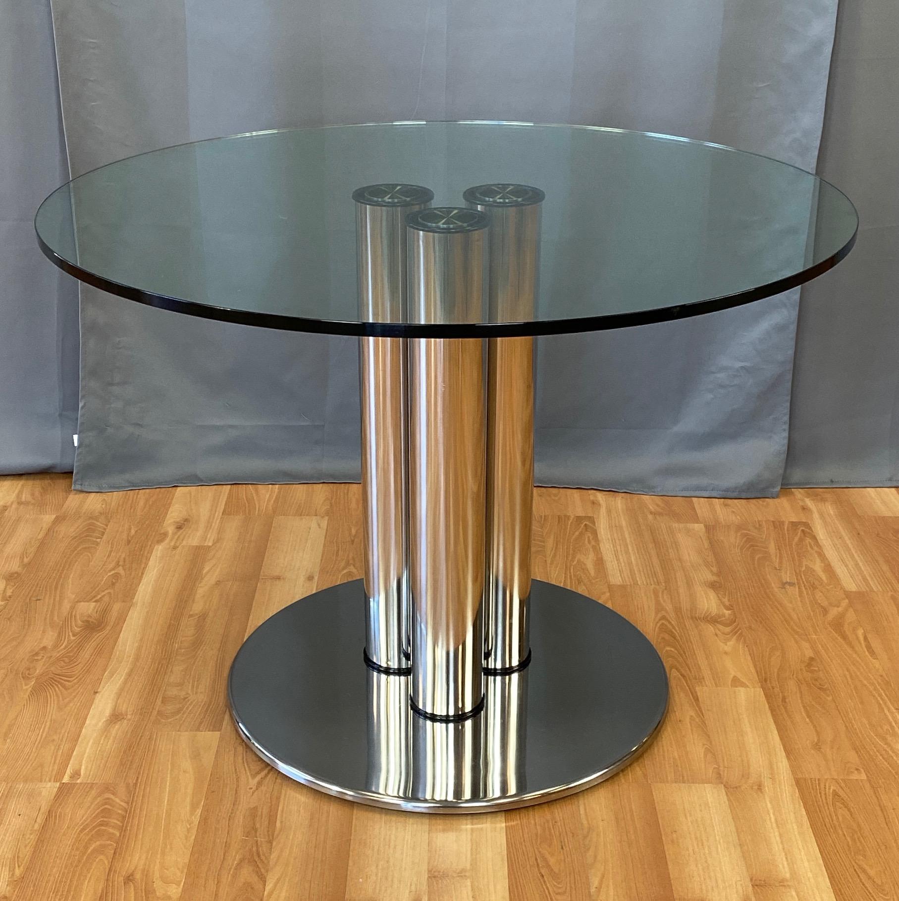 An impressive 1970 polished stainless steel and glass model 2532 Marcuso dining table by important and influential Italian architect and designer Marco Zanuso for Zanotta.

Modernist architectural form comprised of a trio of four inch diameter