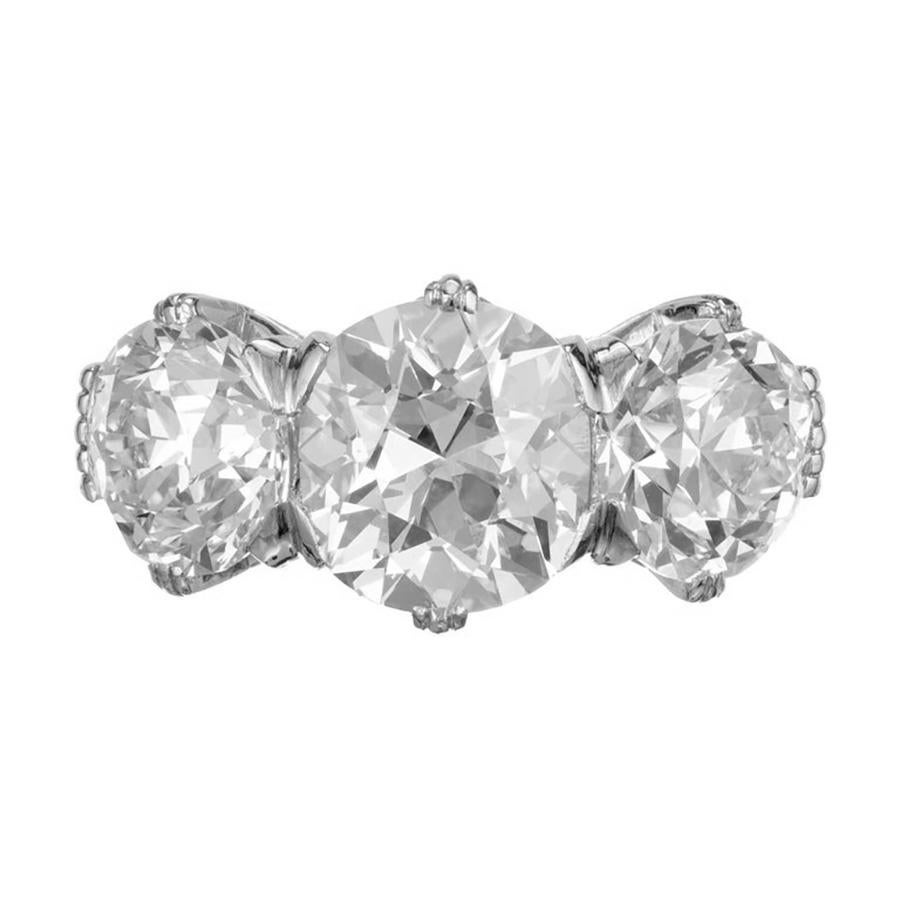 Marcus + Co 1920's Art Deco three-stone diamond platinum engagement ring. Crafted to captivate, this spectacular ring begins with a GIA certified 2.83 carat old mine cute center diamond. Mounted in a platinum three-stone setting and accented by two