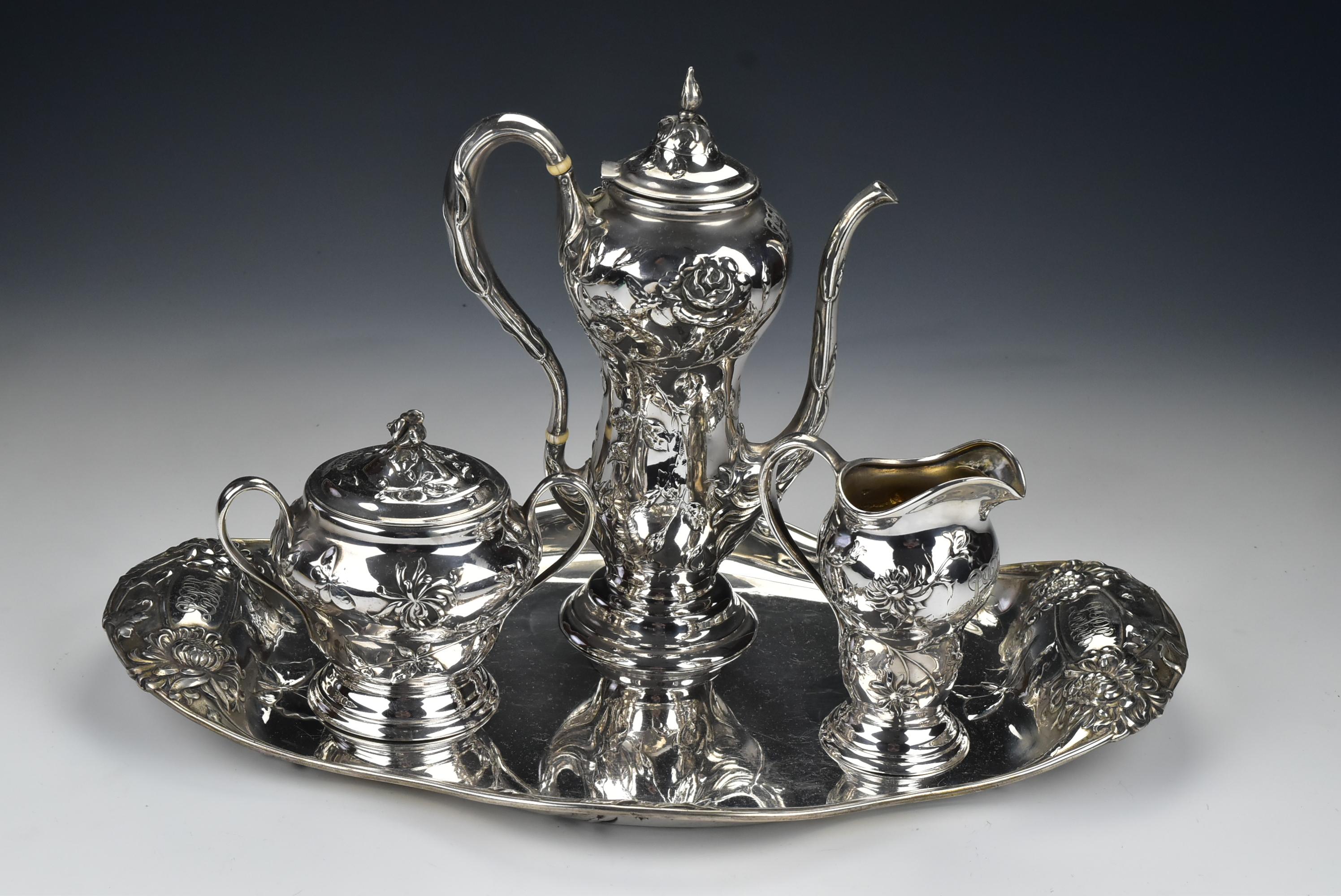 Description: Four-piece sterling silver Art Nouveau cocoa hot chocolate set includes a cocoa pot, covered sugar bowl, creamer, and tray decorated with a fancy monogram and repousse flowers with insects. Each piece is marked Marcus & Co., sterling,