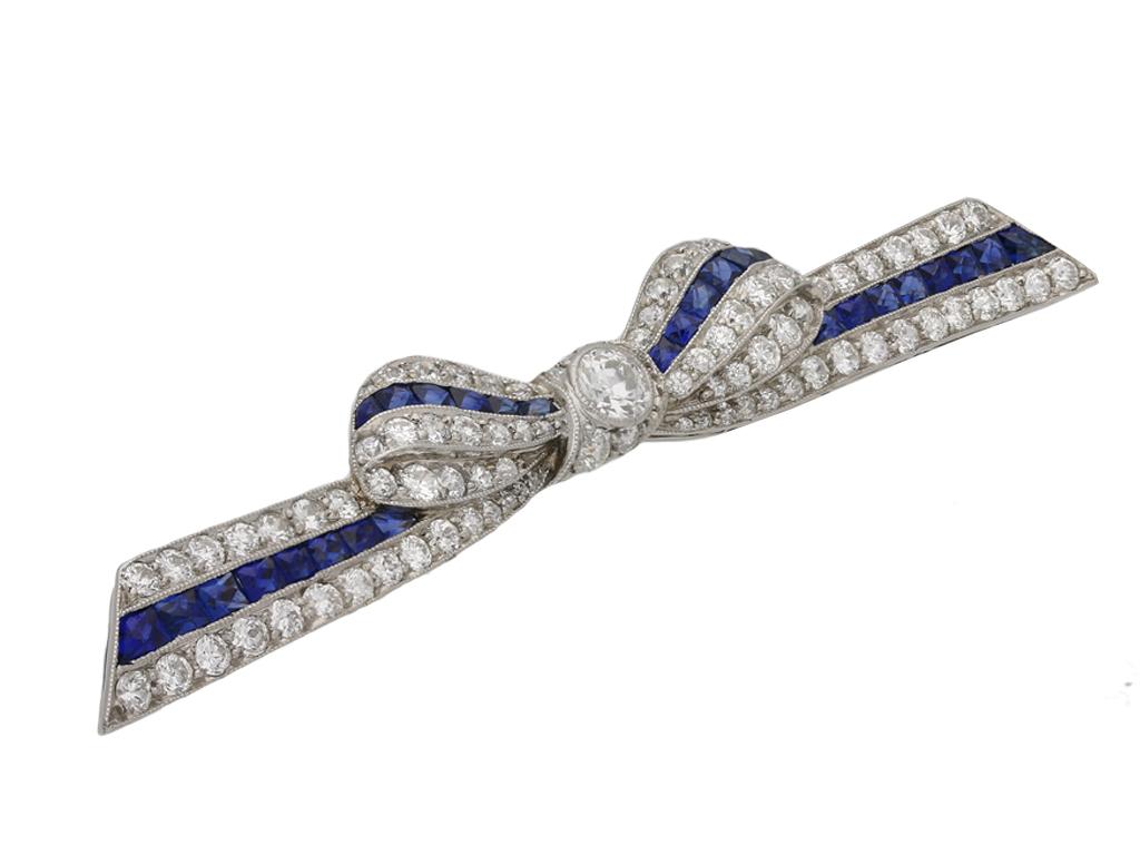 Sapphire and diamond bow brooch by Marcus & Co, American, circa 1935. A yellow gold and platinum bow form brooch set with one central row of twenty eight French cut sapphires in channel settings with an approximate total weight of 2.50 carats,