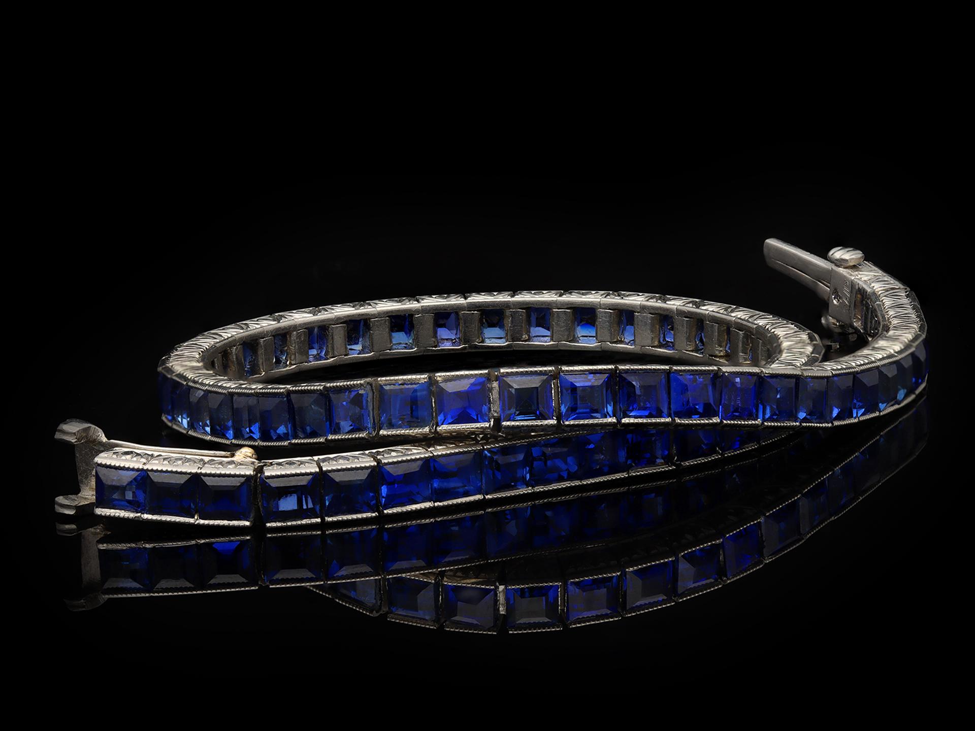 Marcus & Co. sapphire line bracelet. Set with sixty four square step cut natural unenhanced sapphires in open back half rubover and channel settings with a combined approximate weight of 8.30 carats, to a fully articulated line bracelet with