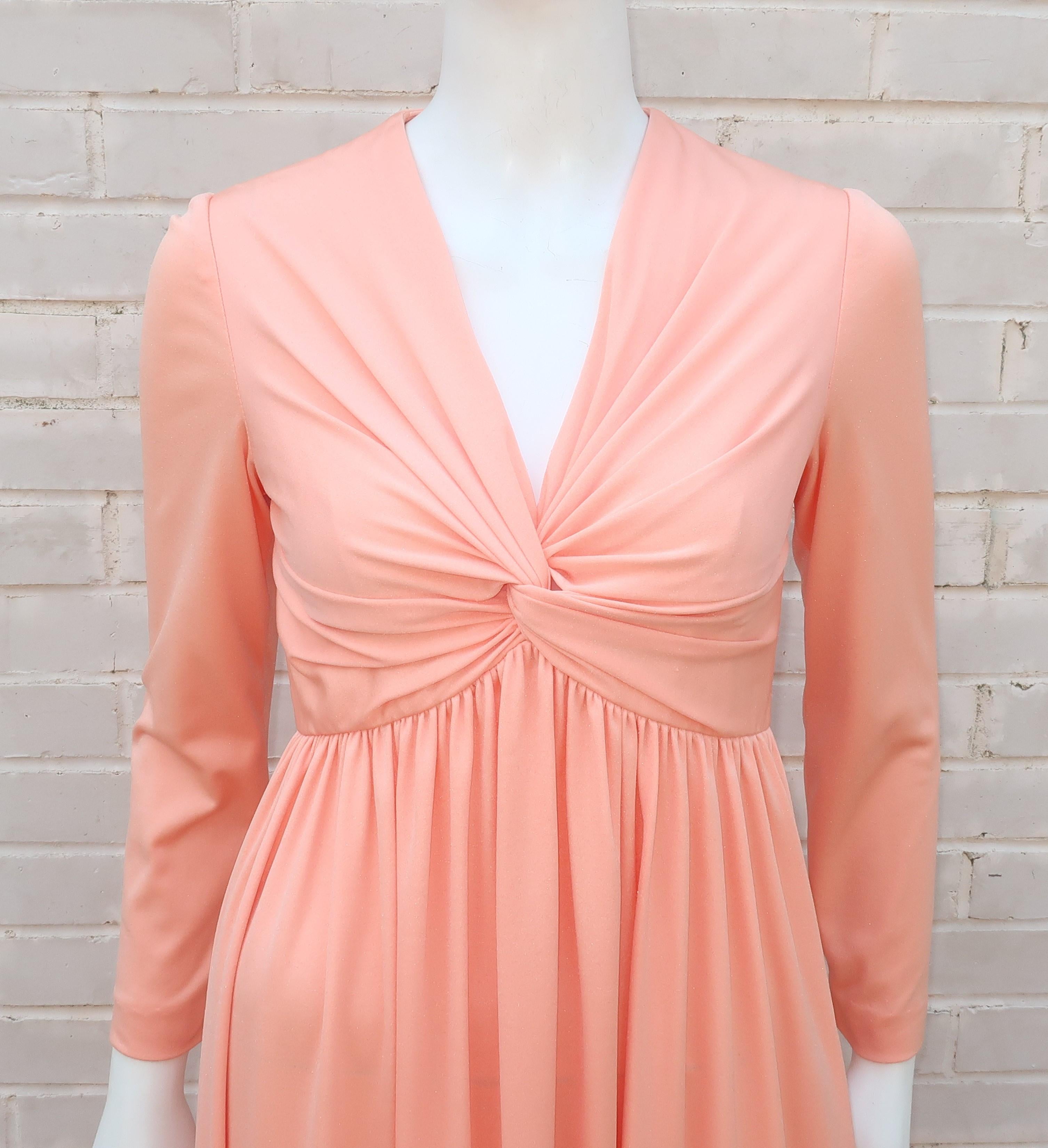 You'll lead the fashion parade when wearing this C.1970 Mardi Gras of New York jersey evening dress.  The peachy sherbet shade compliments the flattering empire waist silhouette complete with a ruched twist at the bust.  It zips and hooks at the