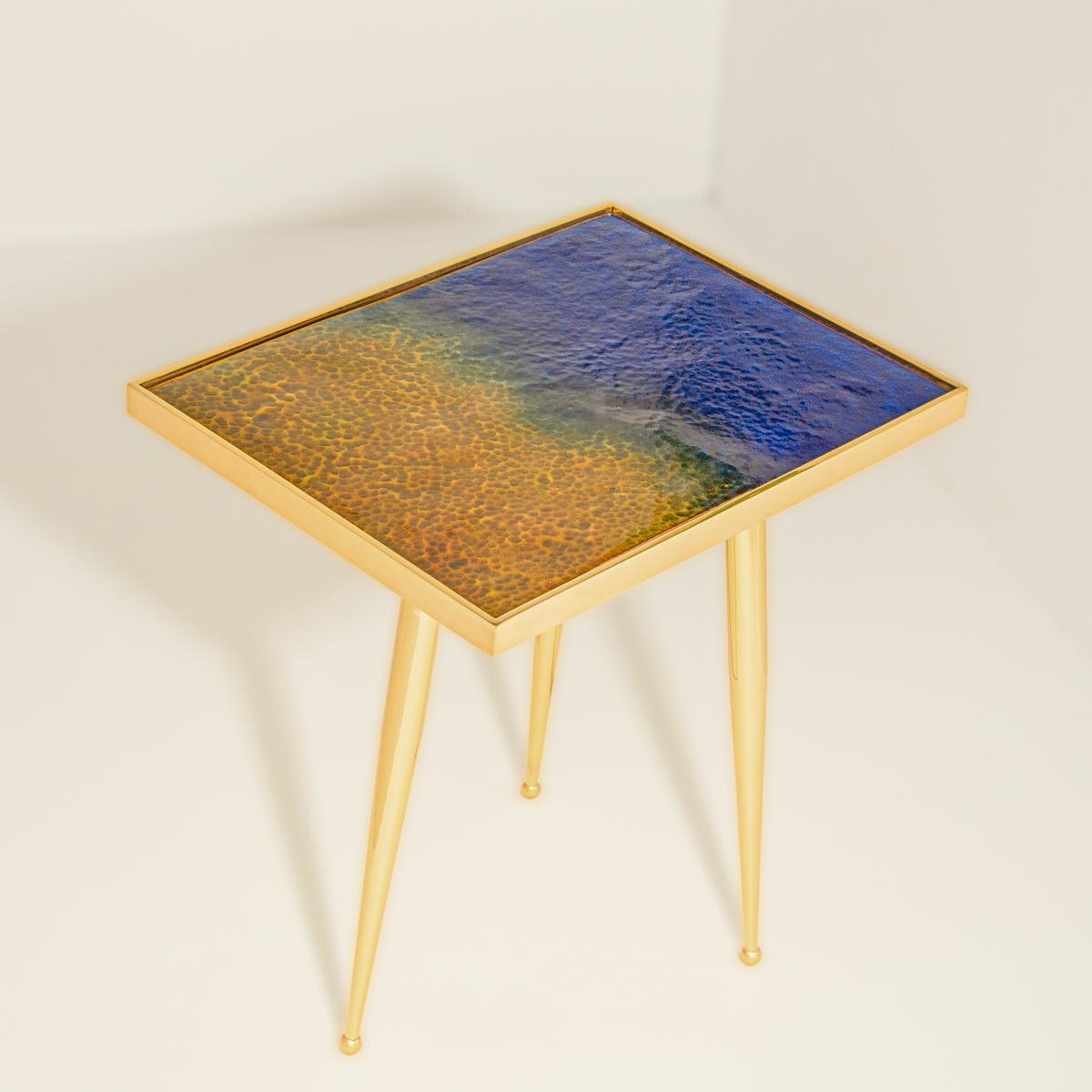 The Marea Estate side table is the first installment of the Marea series depicting the four seasons via enameled tops handmade in Puglia. This iteration represents a Mediterranean summer with its dark blue waters and golden sand