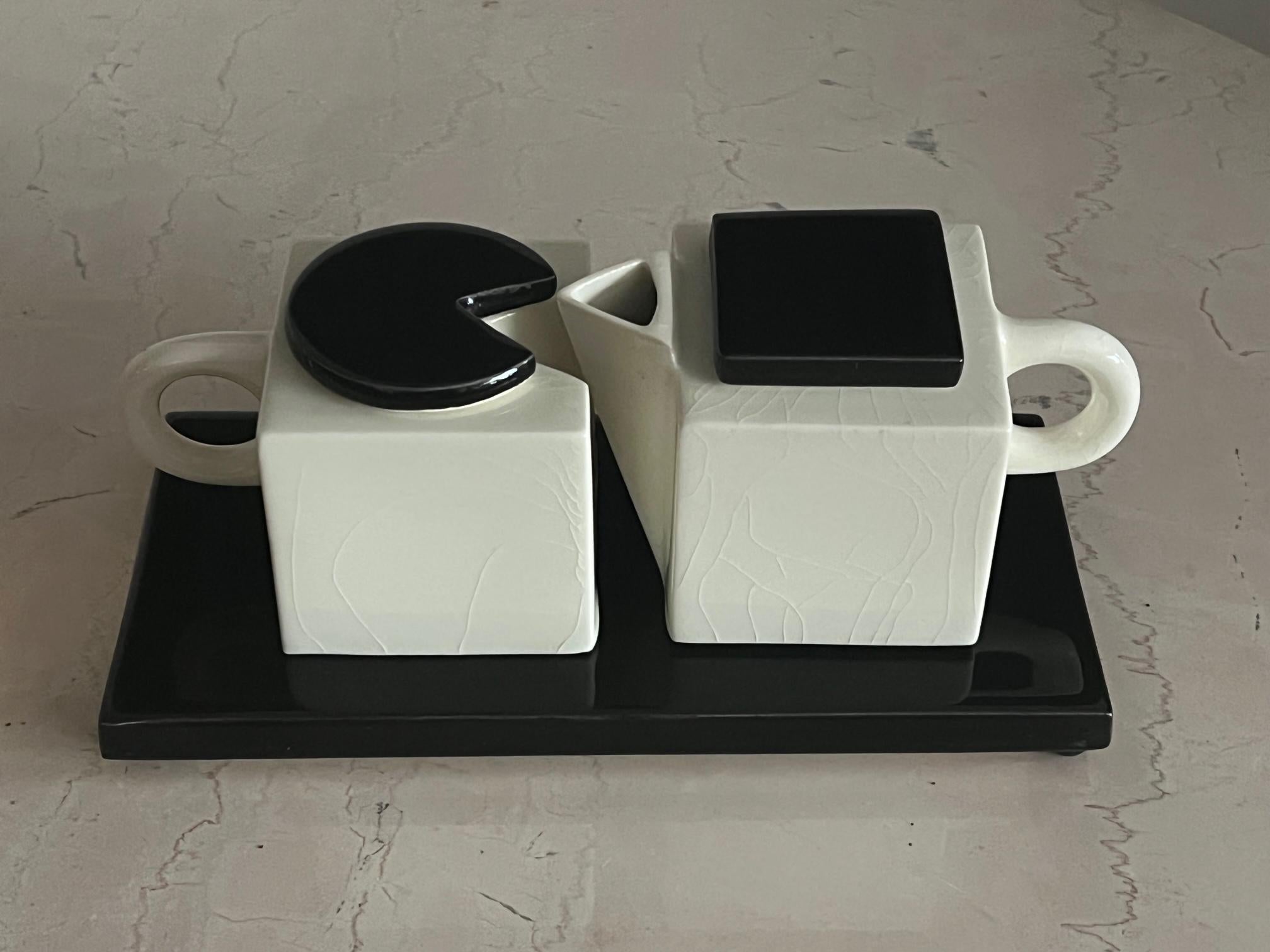 A highly unusual, post modern, creamer/sugar ceramic set by Marek Cecula. The two pieces nest into each other, while on a pedestal. A great example of Marek Cecula work.