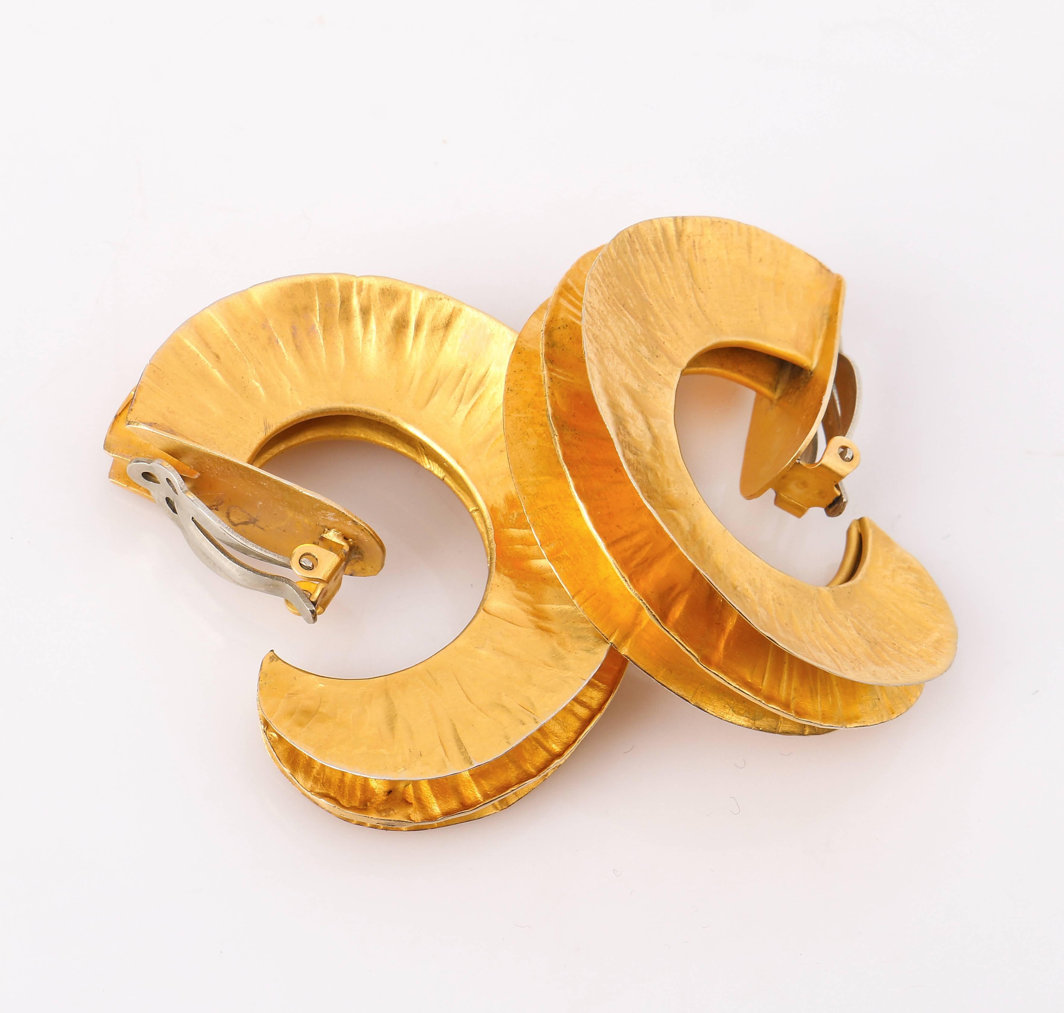 Margaret Ellis c.1991 artisan handcrafted bronze tone metal large hoop clip on statement earrings. Bright bronze tone metal hoop earrings have a gently hammered texture. Body of the earring is three fused ring. Large horn shaped hoop earrings