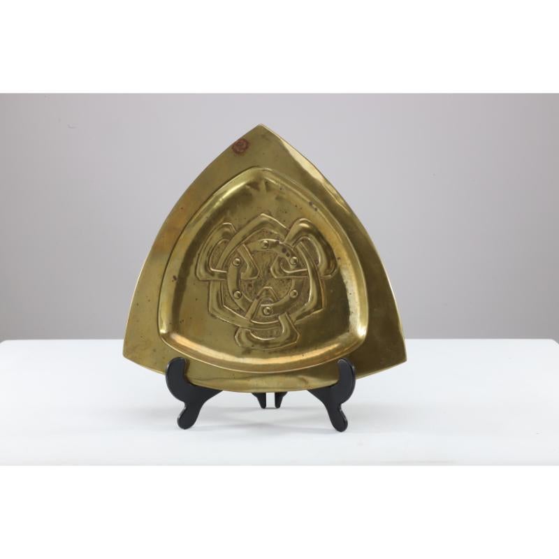 Margret Gilmour school. An Arts and Crafts Glasgow School brass pin or card tray with Celtic interlaced decoration. Its triangular shape continues with tri-angular Celtic decoration to the centre with a circular band with roundels within it.
