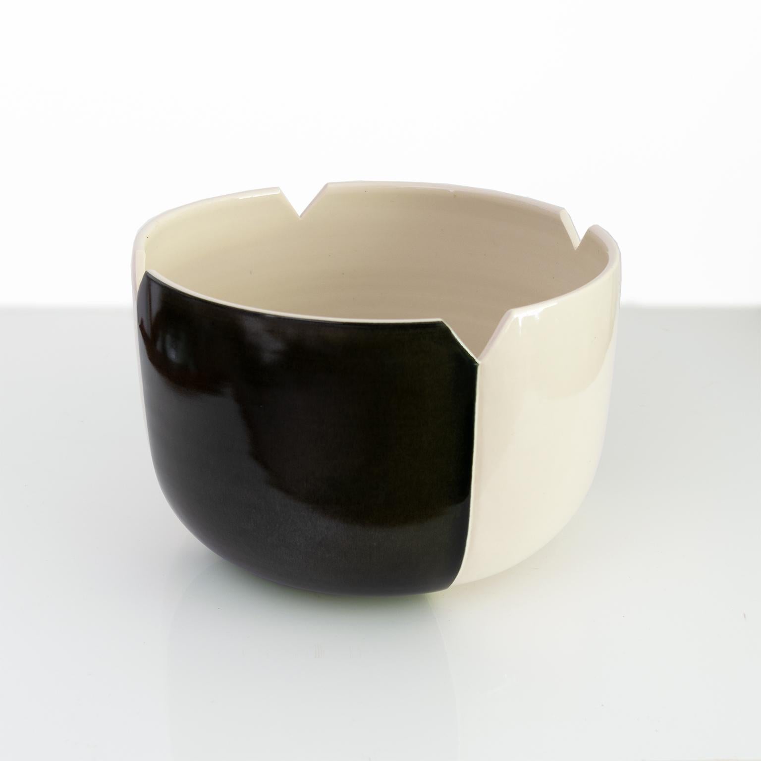 Una grande ciotola da studio disegnata da Margareta Hennix con smalti marrone scuro-nero e bianco crema. Quattro intagli dettagliano il bordo della ciotola e un piede basso eleva la ciotola. Firmato sul fondo con data 1982, realizzato a Gustavsberg,