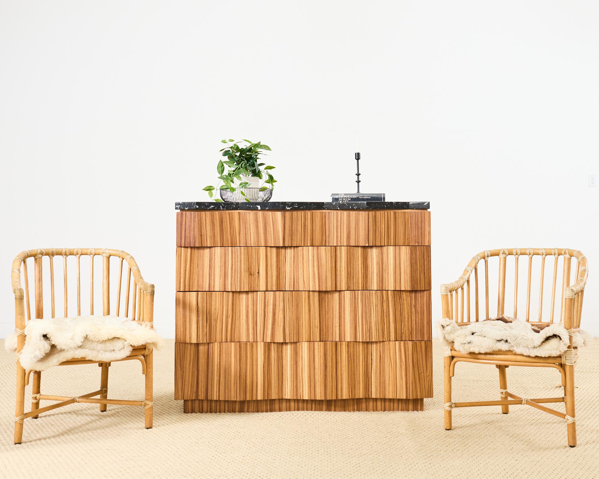 Éblouissante commode à quatre tiroirs en bois plaqué, avec un épais plateau de marbre. Le coffre a été conçu par Marge Carsons avec des façades de tiroirs en serpentin et des marbres qui ajoutent à la complexité et à la texture des bois rayonnants