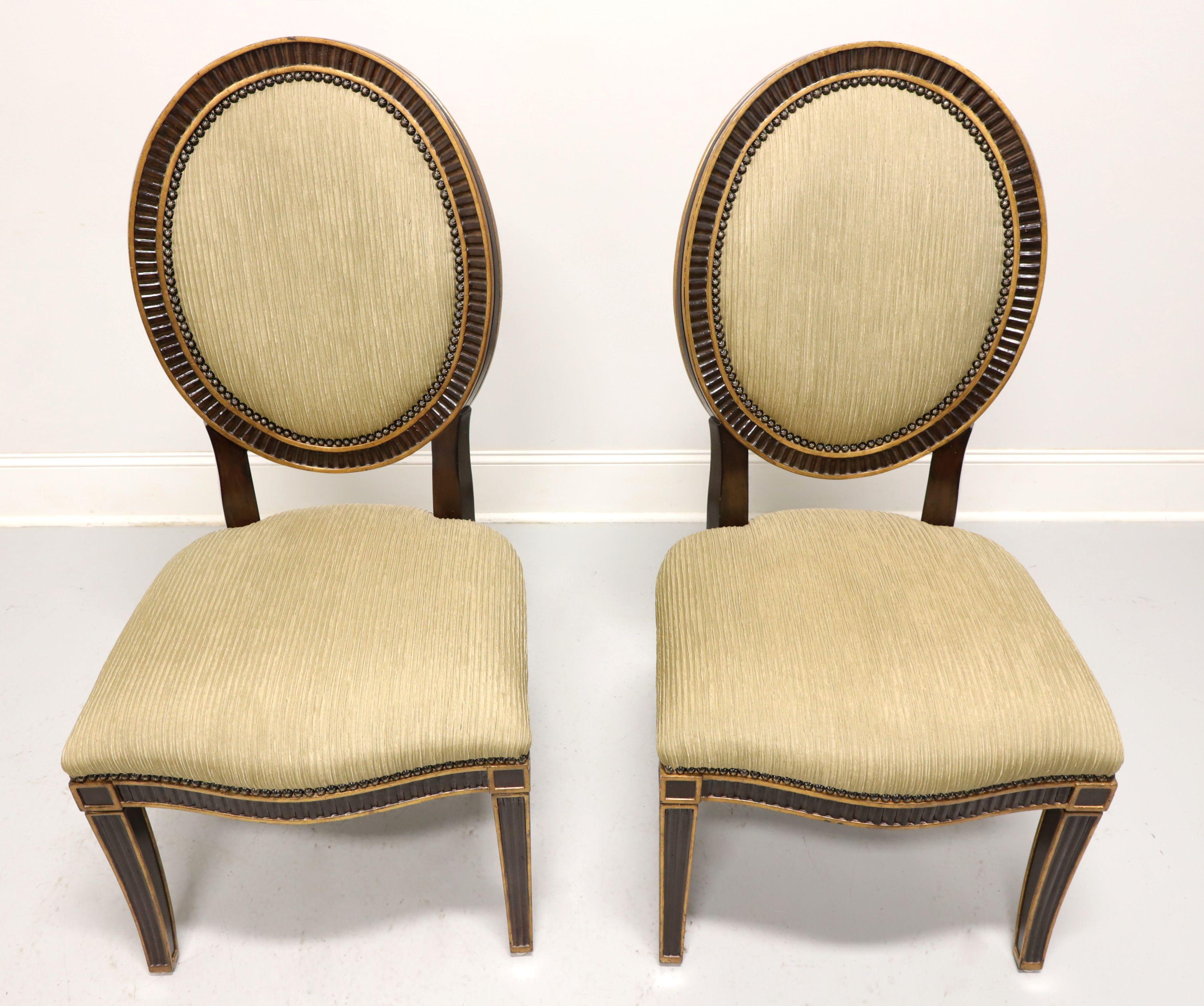 A pair of Contemporary French style dining side chairs by high-end furniture maker Marge Carson, of Pomona, California, USA, from their Rue Royale Collection. Solid hardwood with a dark finish, gold painted accents, decoratively fluted oval back,