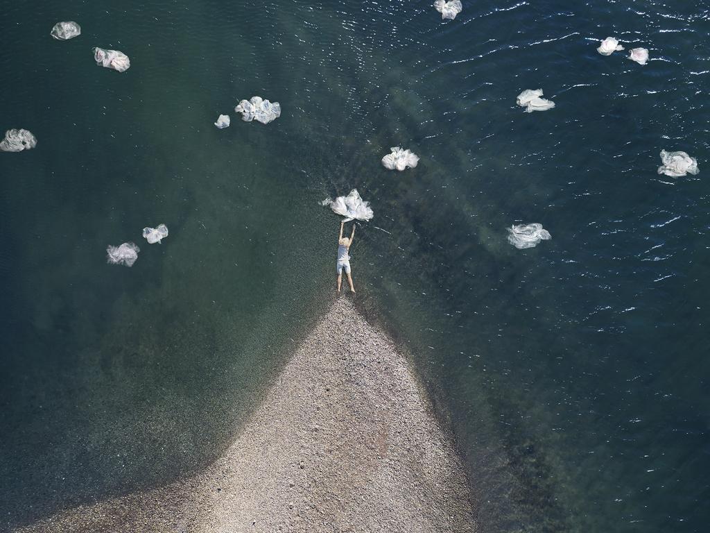 Margeaux Walter Color Photograph - Cumulus - Woman figure floating in ocean water, beach coast, plastic bag clouds