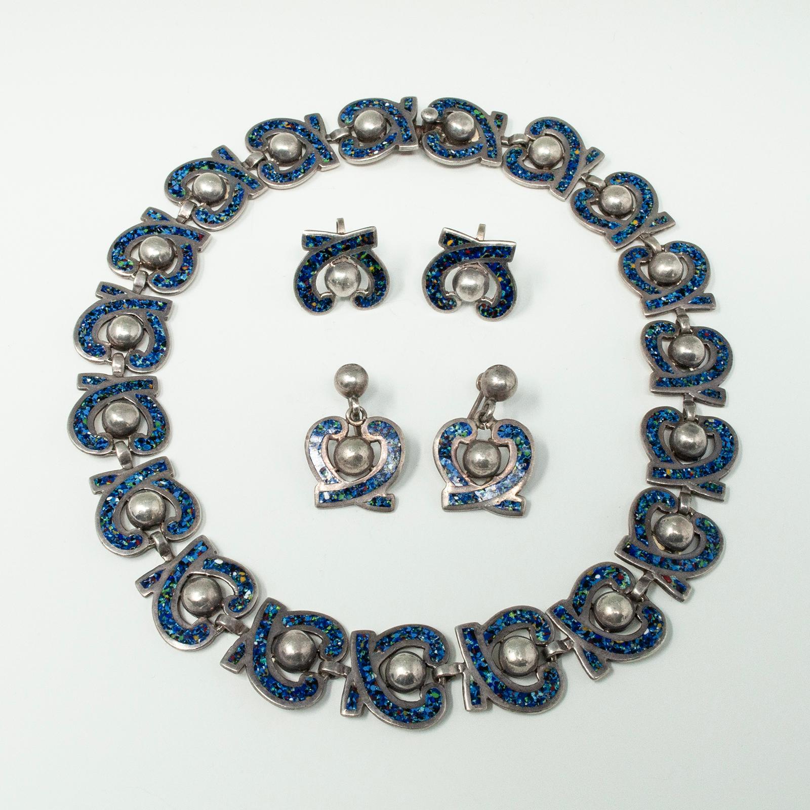 Margot de Taxco Collier en émail et argent et deux paires de boucles d'oreilles
Le motif est un cœur et une boule stylisés. Design/One #5463.
Le collier et les boucles d'oreilles sont en émail confetti de style champleve sur argent sterling.
Les