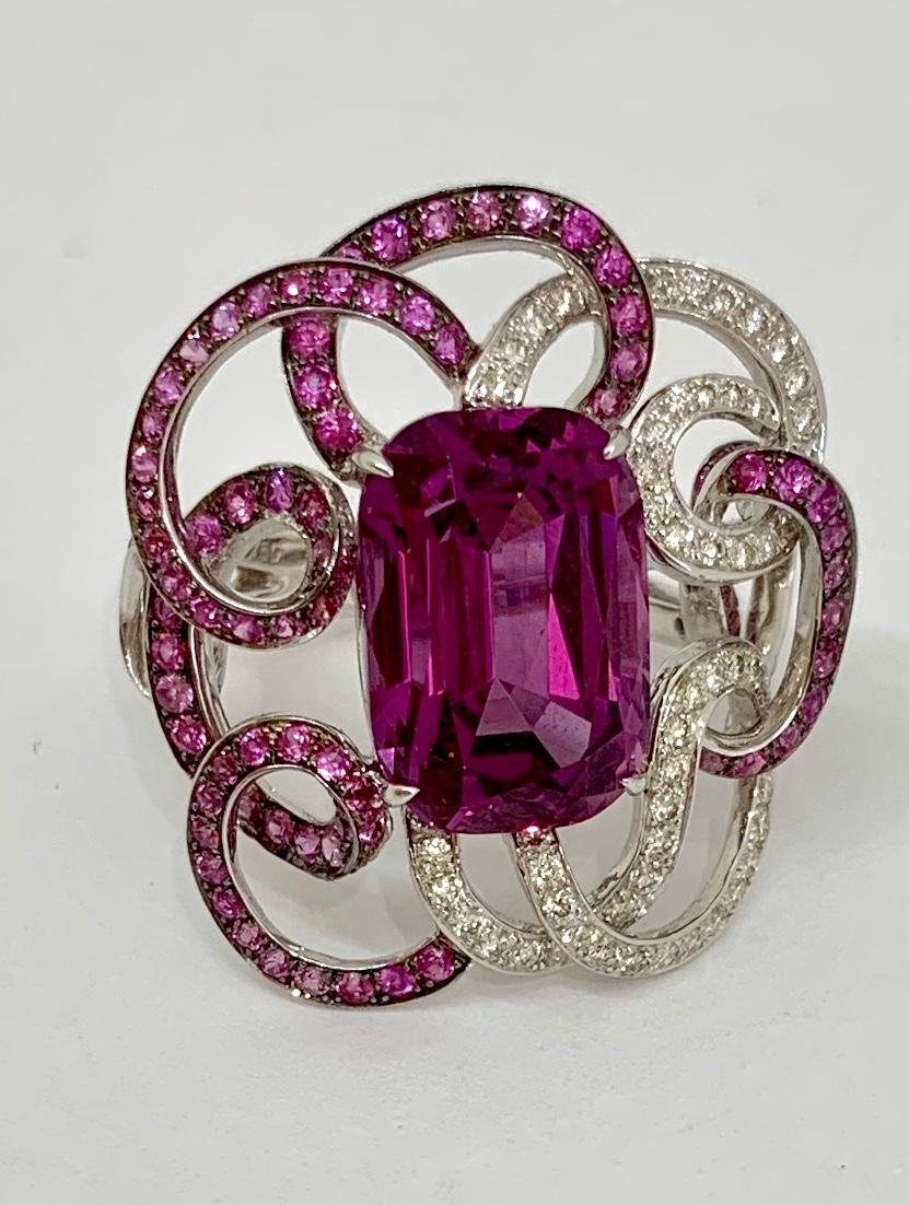 Margot McKinney 18 Karat White Gold 'Swirl' Ring is set with 1 cushion cut Pink Garnet 10.40ct surrounded by a swirl of 75 Diamonds 0.61ct and 114 Pink Sapphires 1.41ct. 
Size USA 6 1/4 (UK/AU Size M).
