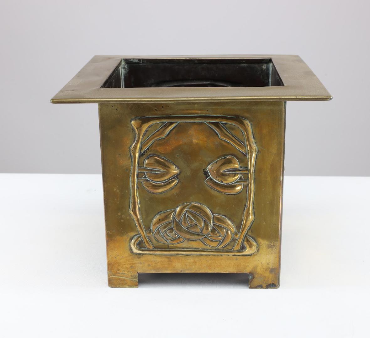 Margaret Gilmour attribuée. Une jardinière en laiton de l'école Glasgow Arts and Crafts, ornée d'une rose stylisée et de détails floraux sur tous les côtés, reposant sur des pieds triangulaires typiques des studios Gilmour.