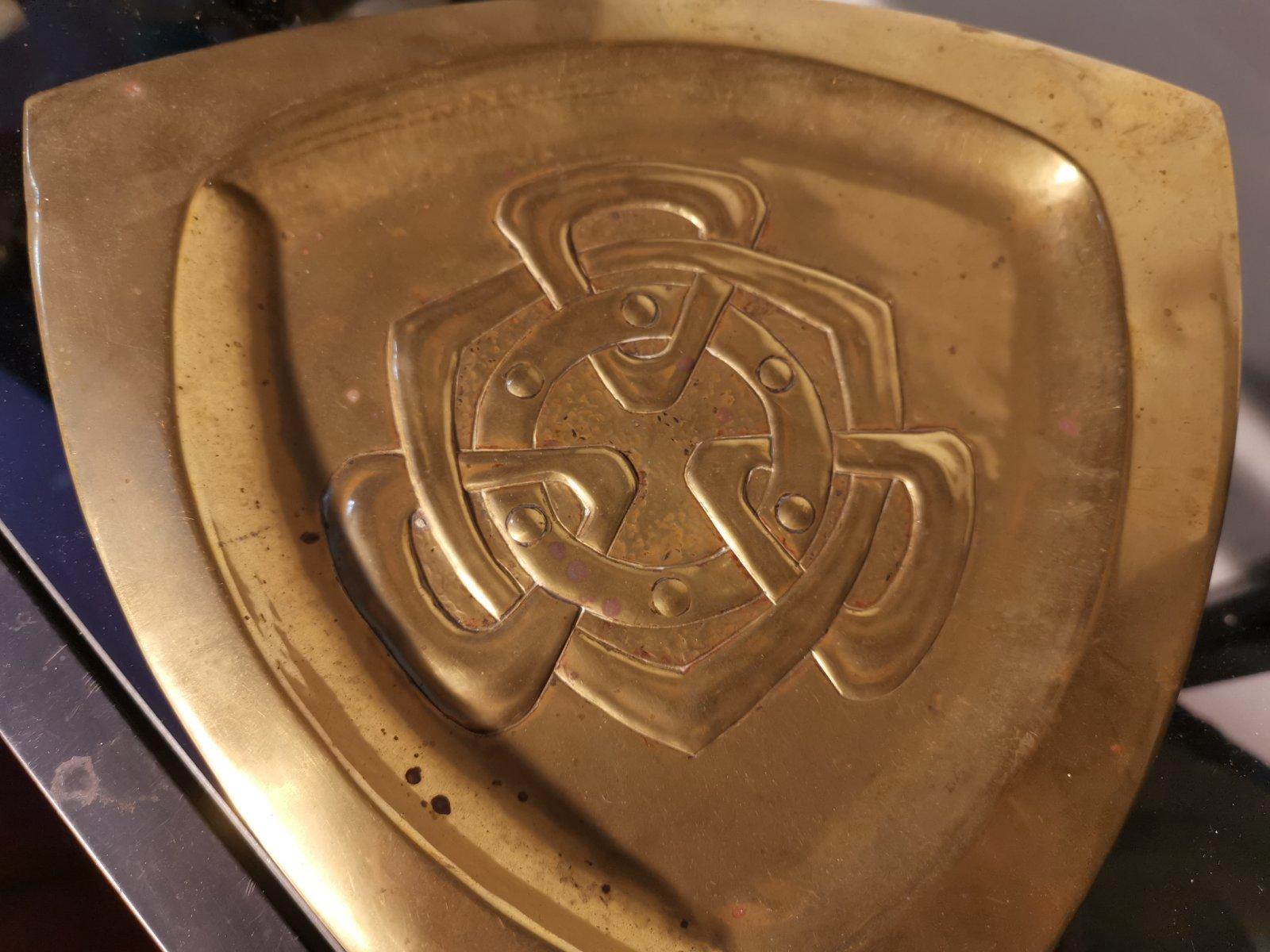Margret Gilmour school.
An Arts and Crafts Glasgow School brass pin or card tray with Celtic interlaced decoration. 
Its triangular shape continues with tri-angular Celtic decoration to the center with a circular band with roundels within it.