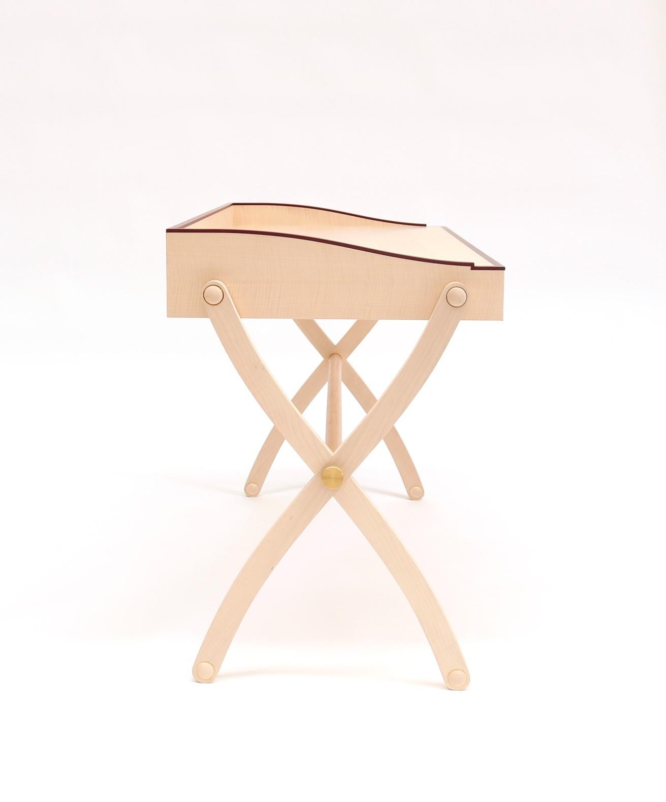 Marguerite is an elegant writing desk made of maple wood with a thin edging in amaranth wood. A pen tray made of amaranth wood is built on the top, closed by a rounded lid.
The writing desk has two drawers.
The cross legs are decorated with