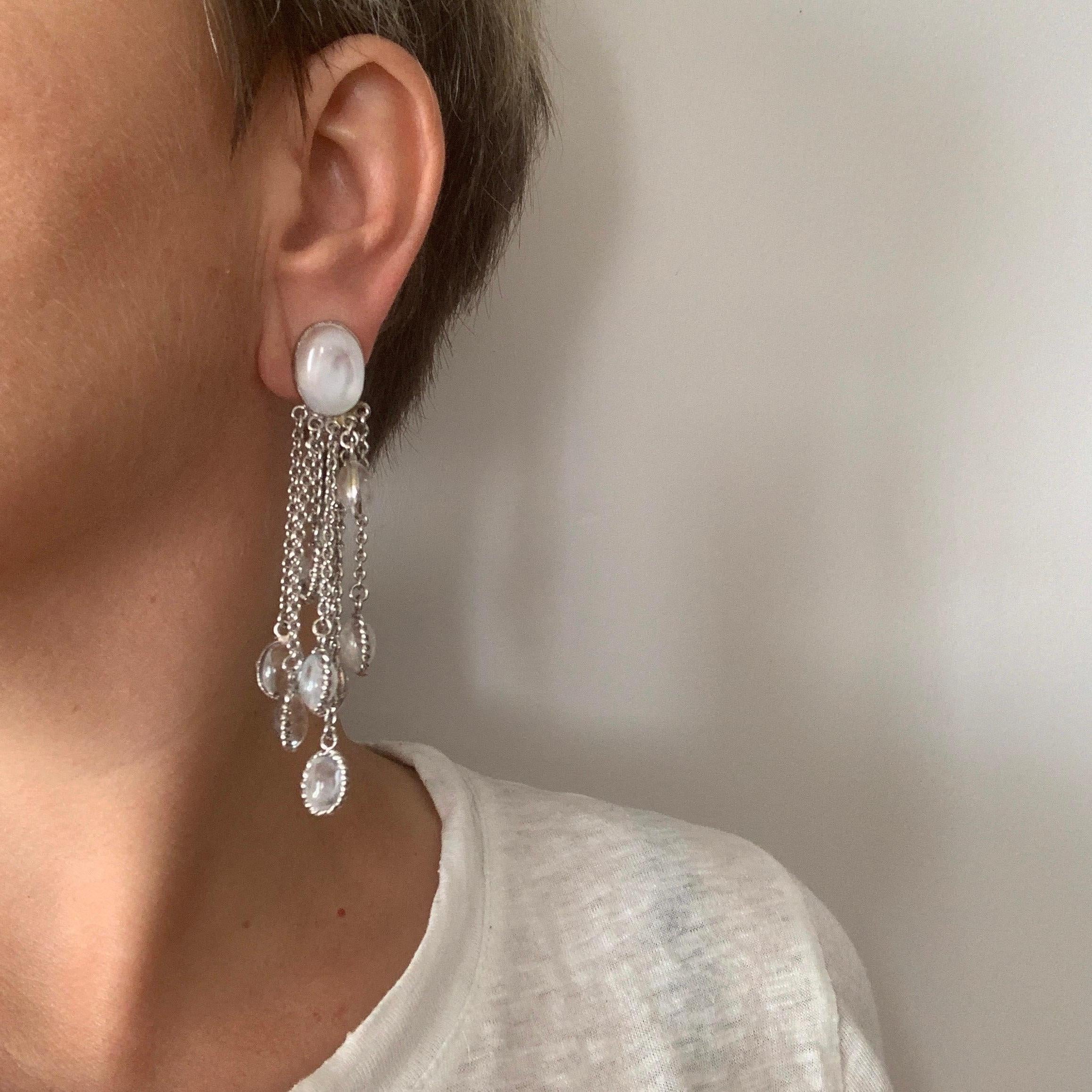 MARGUERITE DE VALOIS dangling clip-on earrings. Oval piece in white molten glass at the level of the clasp, on which are suspended 8 silver metal chains at the end of which hang other ovals in transparent white molten glass.
They were made by French
