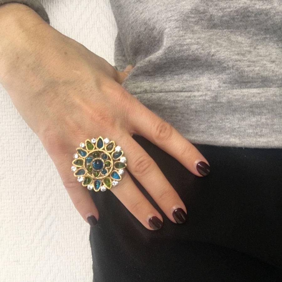 Beautiful MARGUERITE DE VALOIS ring in gilded metal with fine gold, set with blue and green stones in molten glass and rhinestones.

New condition.

Ring adjustable from size 50 and beyond.

Marguerite de Valois house makes its jewelry in its