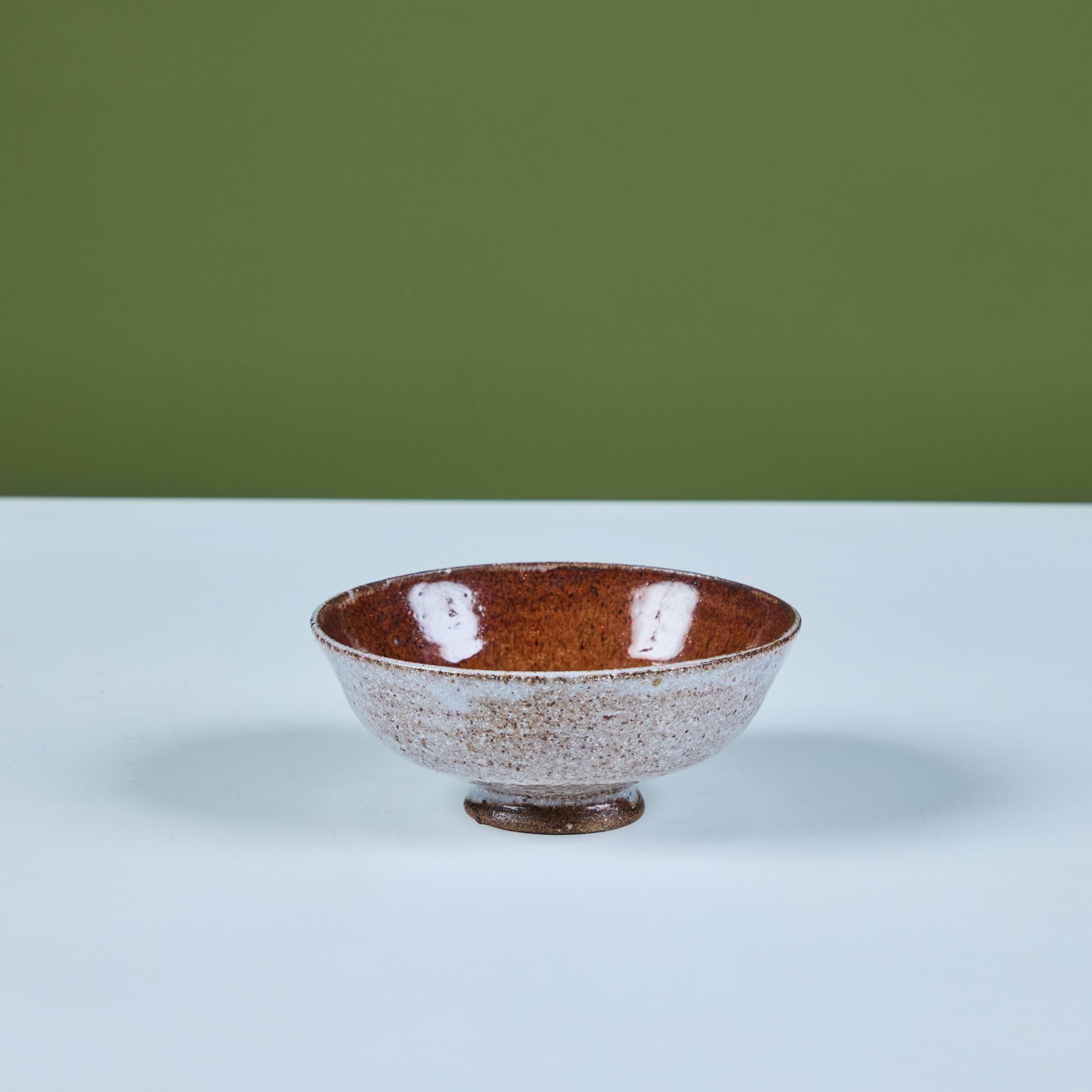 Cuenco de cerámica arrojada a mano por la artista de la Bauhaus Marguerite Wildenhain c.1940s, EEUU. El cuenco con pie presenta un vidriado exterior blanco, con el interior marrón y tostado.

Dimensiones
5,25