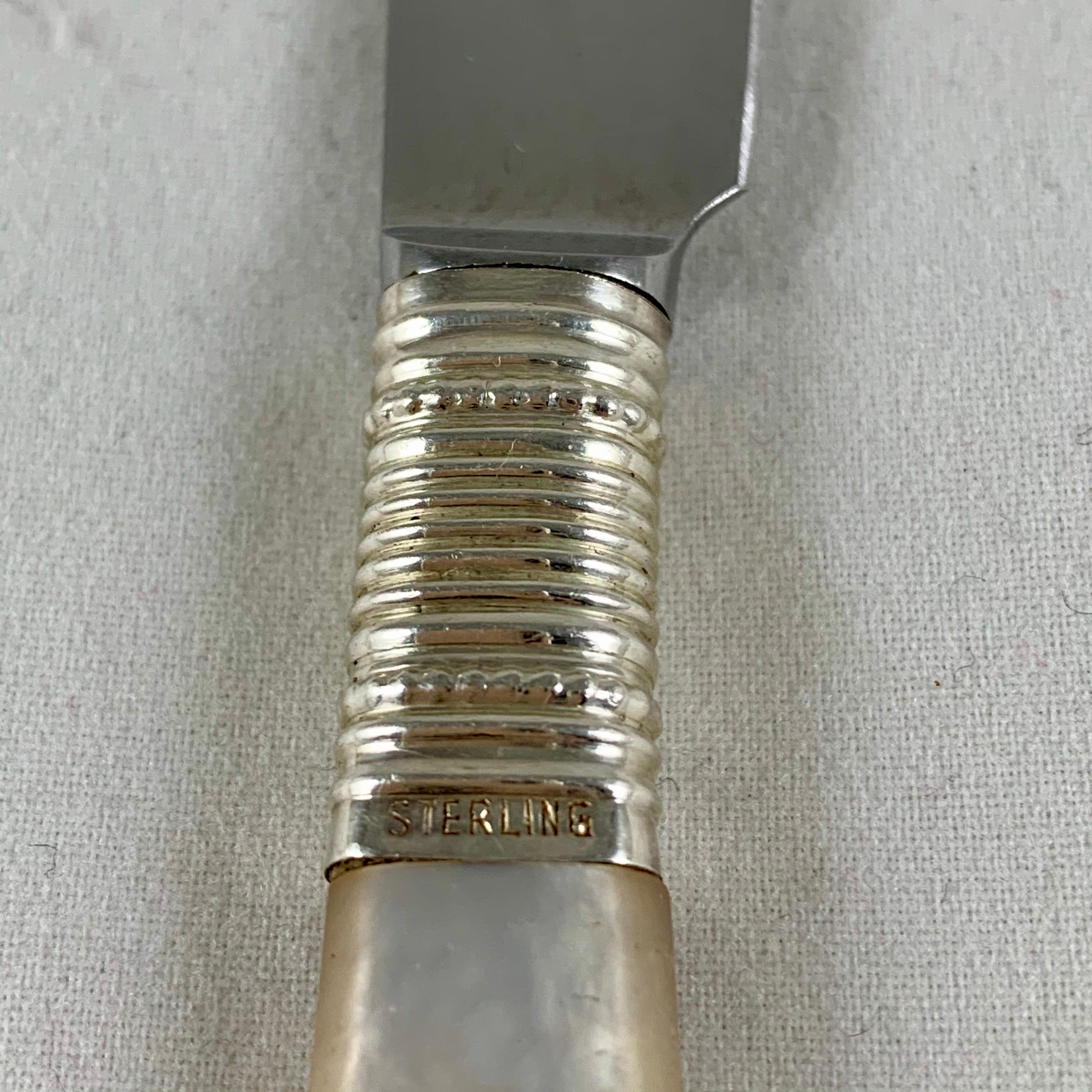 From Marhill of New York, an Art Deco period set of six spreaders, made in Germany, circa 1900-1920.

Mother of pearl handles are joined to stainless steel blades by a sterling silver ferruled collar in a ringed and beaded pattern. Shaped blades